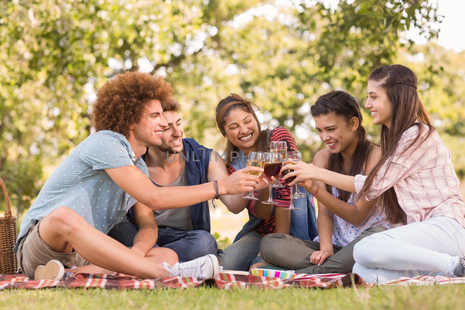 Happy friends in the park having picnic on a sunny day