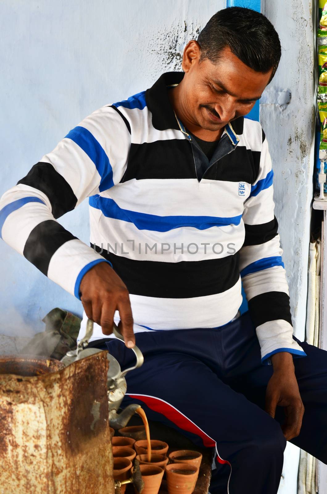 Jaipur, India - December 30, 2014: Indian man pouring milk tea in the terra cotta pottery on December 30, 2014. in Jaipur, India