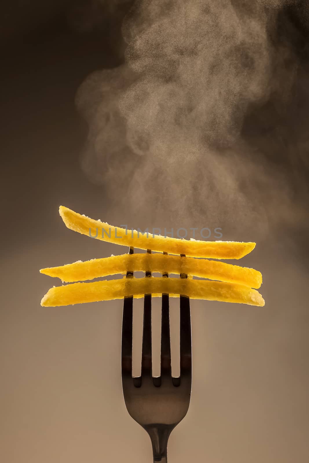 Hot French fries on a fork on a gray background