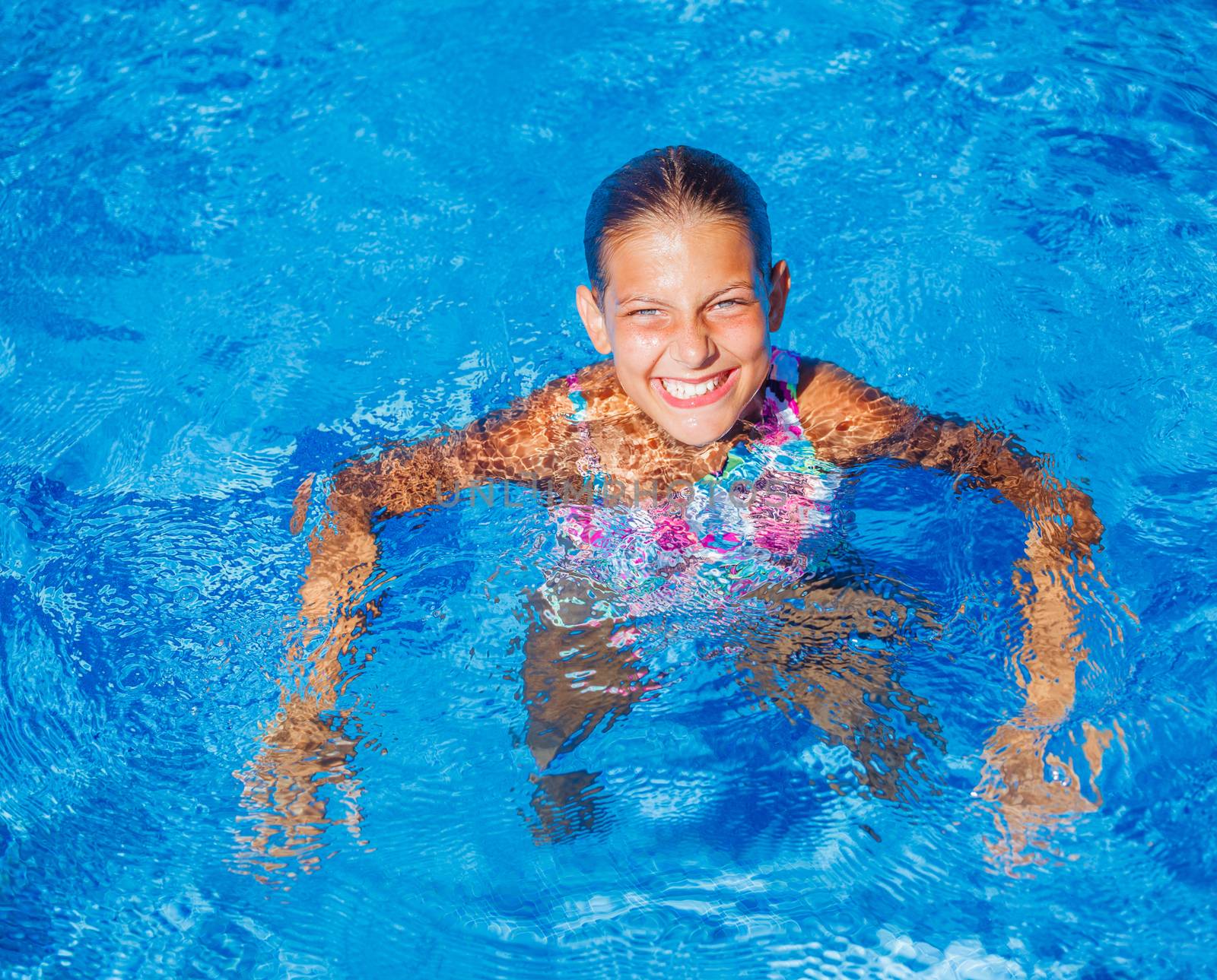 Cute happy young girl swimming and snorking in the swimming pool