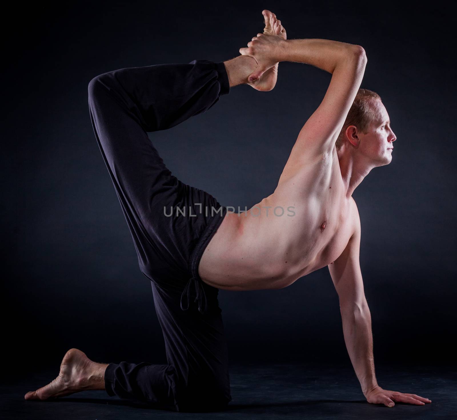 Handsome man doing yoga. Shot on black background