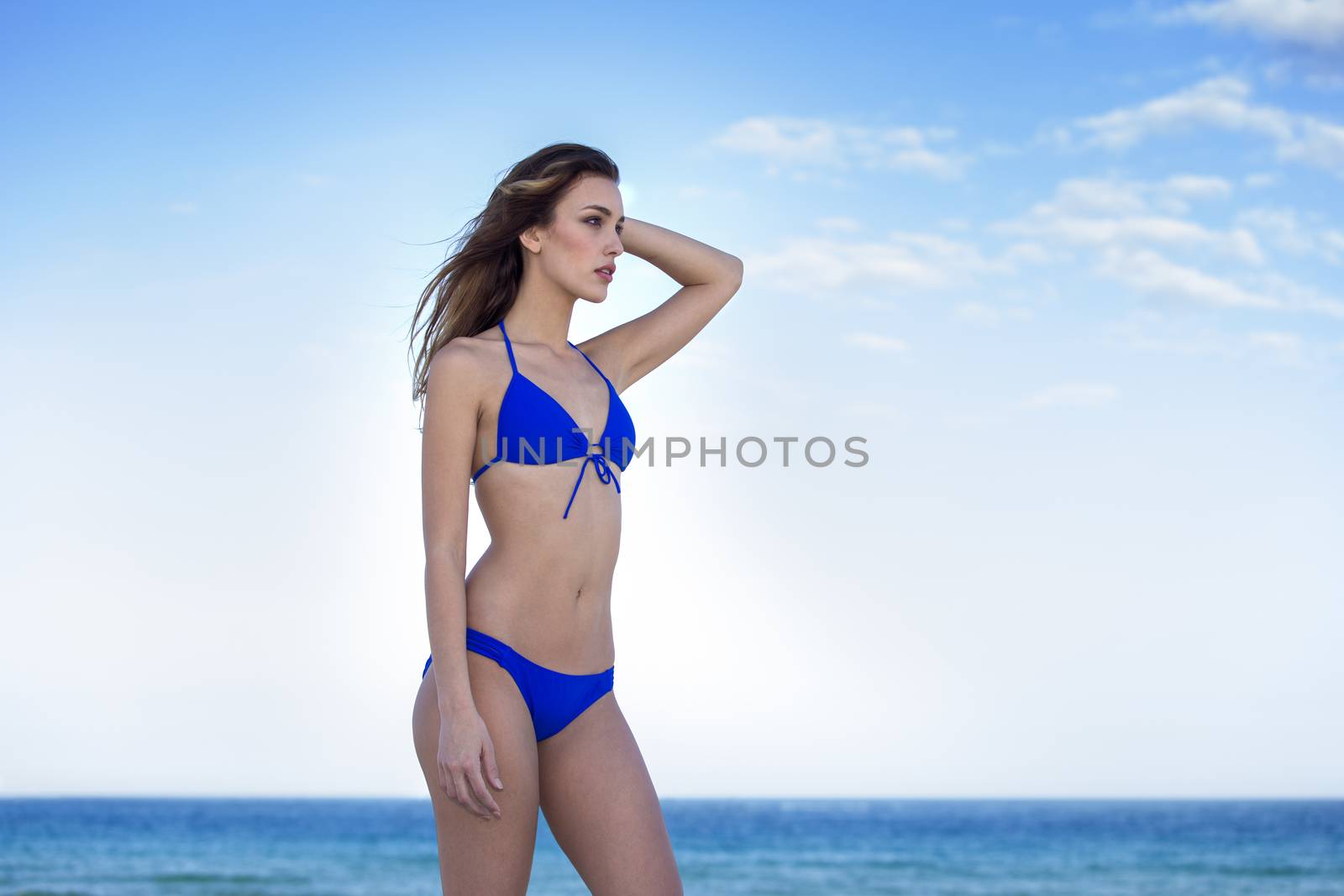 Woman in blue bikini, at the beach. Looking away.