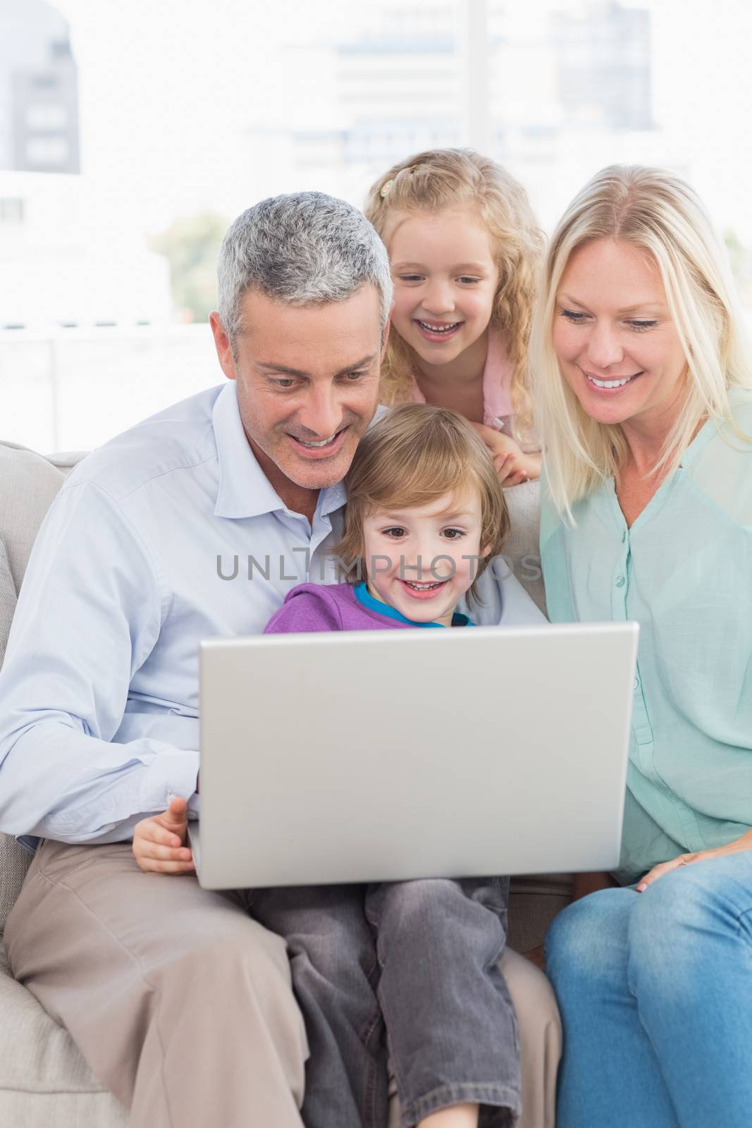Happy family of four using laptop at home