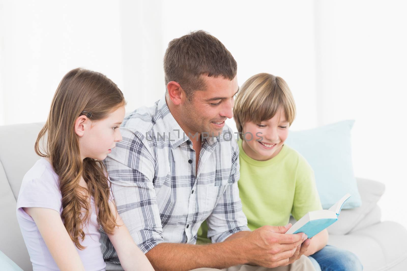 Man telling story to daughter and son while sitting on sofa at home