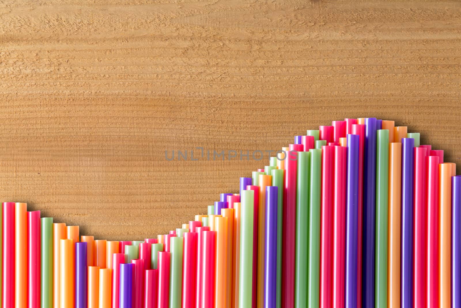 What goes up must come down concept on wood with a wavy line of vivid multicolored drinking straws in an undulating pattern, with copyspace