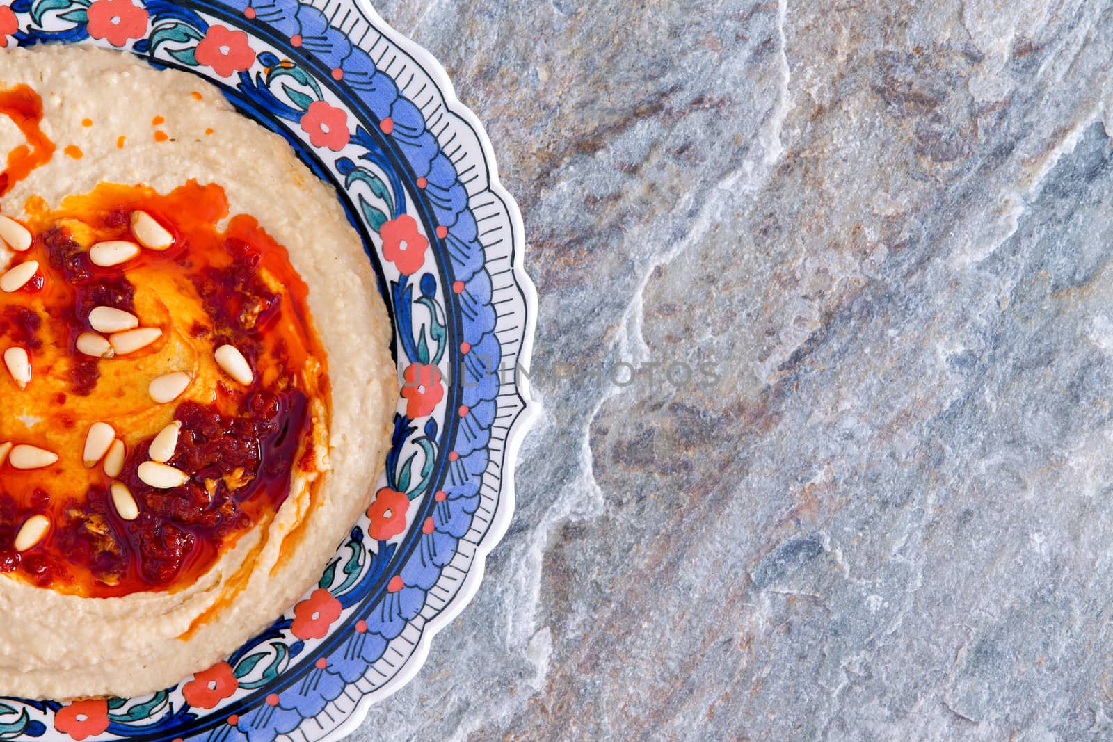 Bowl of hummus on a natural stone countertop by coskun