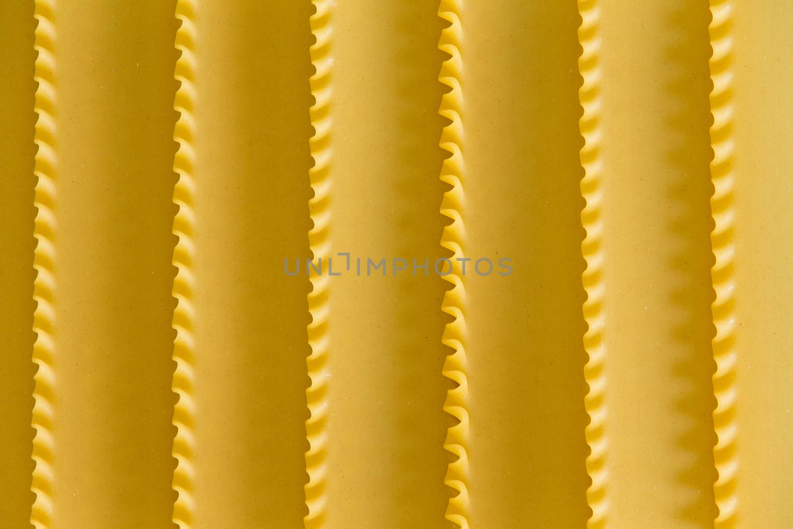 Organic dried durum wheat semolina lasagne background texture with a decorative parallel pattern formed by the crimped edges of the sheets