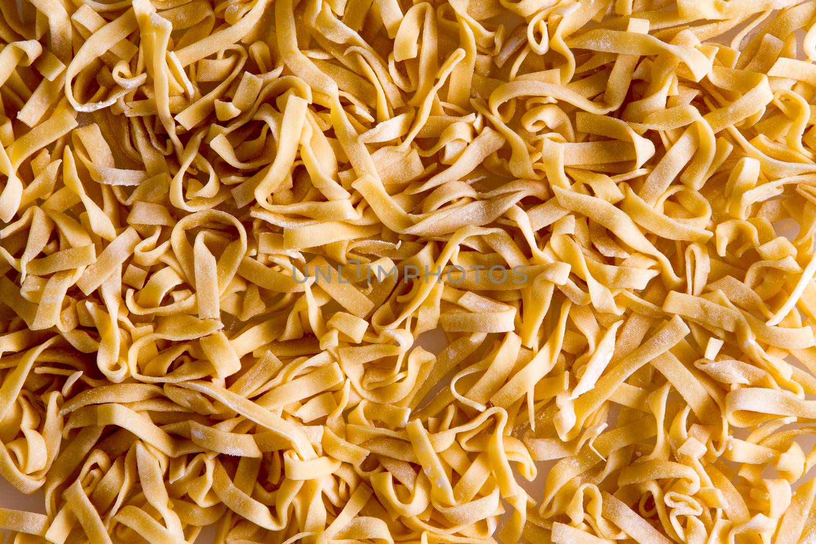 Background of fresh homemade fettuccine pasta noodles in traditional ribbon form made from durum wheat dough, full frame