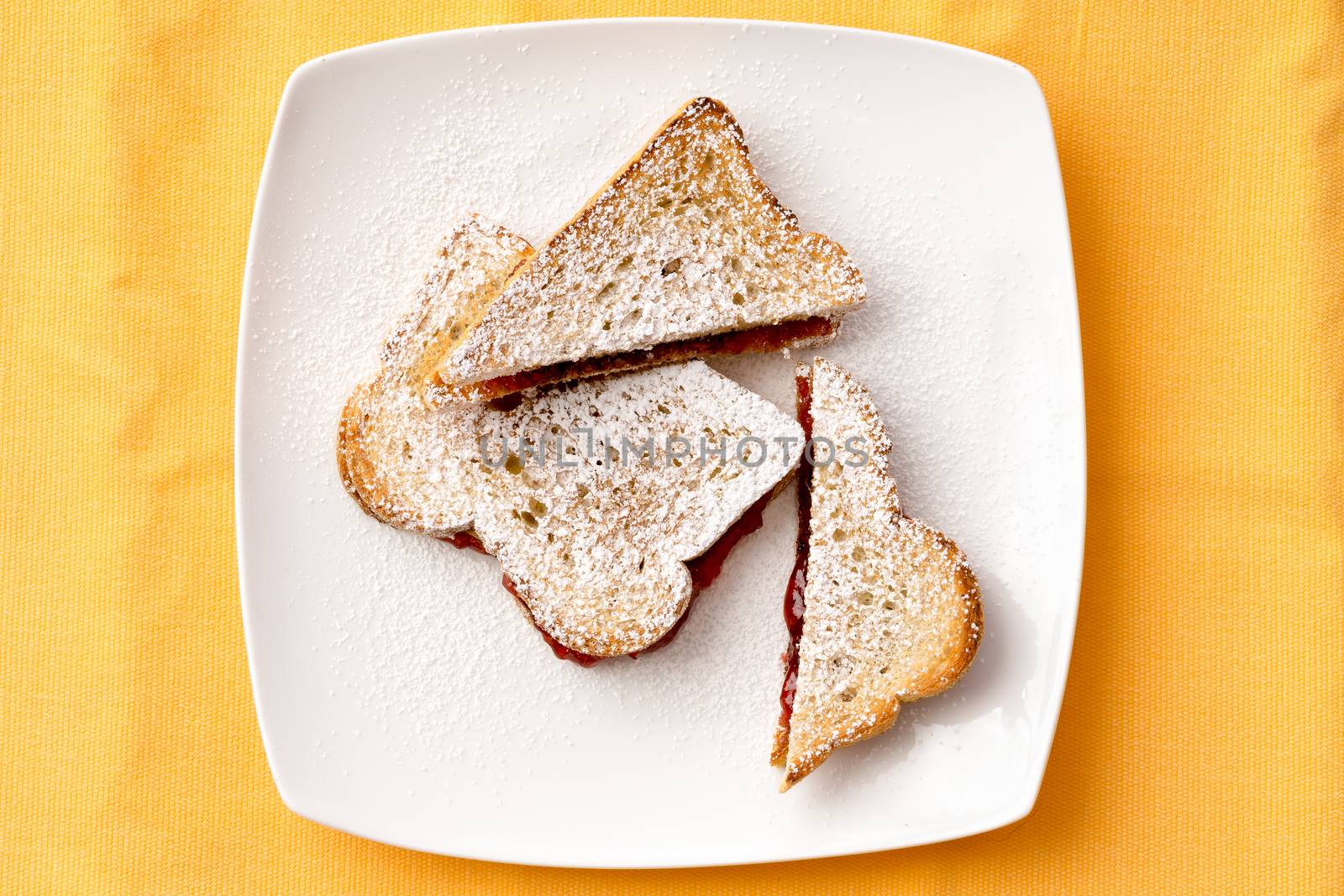 Aerial View of Tasty French Toast Bread with Sweet Strawberry Jam Filling on White Plate for Breakfast. Isolated on Yellow Background.