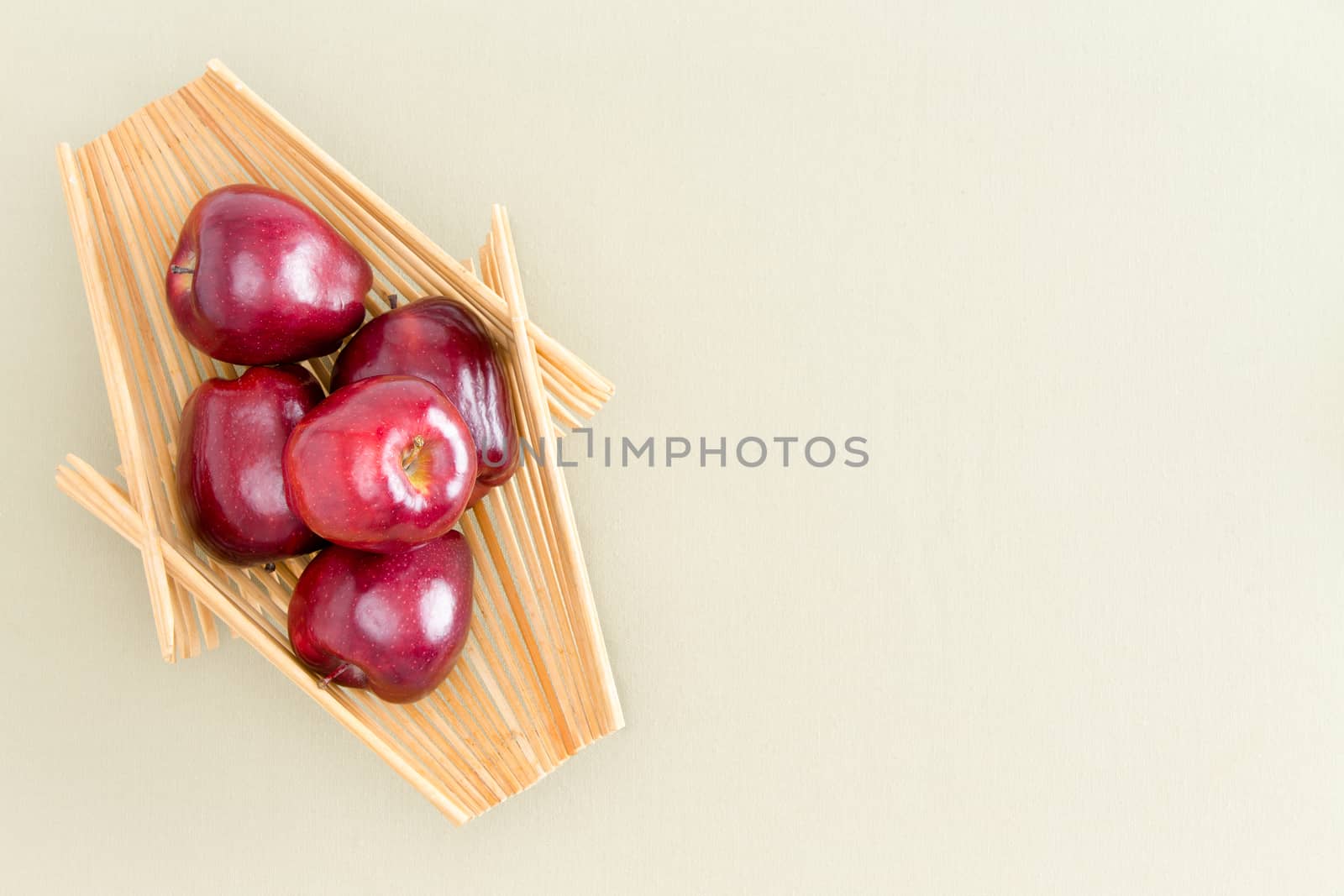 Healthy Fresh Red Apples on a Wooden Tray Placed on Top of a Light Green Table, Emphasizing Copy Space. Captured in High Angle View.