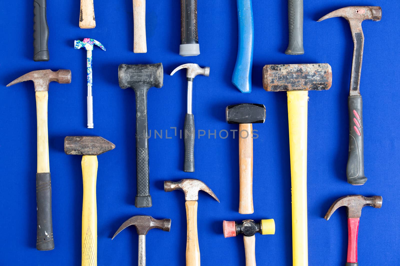 World of hammers with a large assortment of different shapes arranged neatly in vertical lines on a bright blue background in a DIY, carpentry, building, maintenance and renovation concept