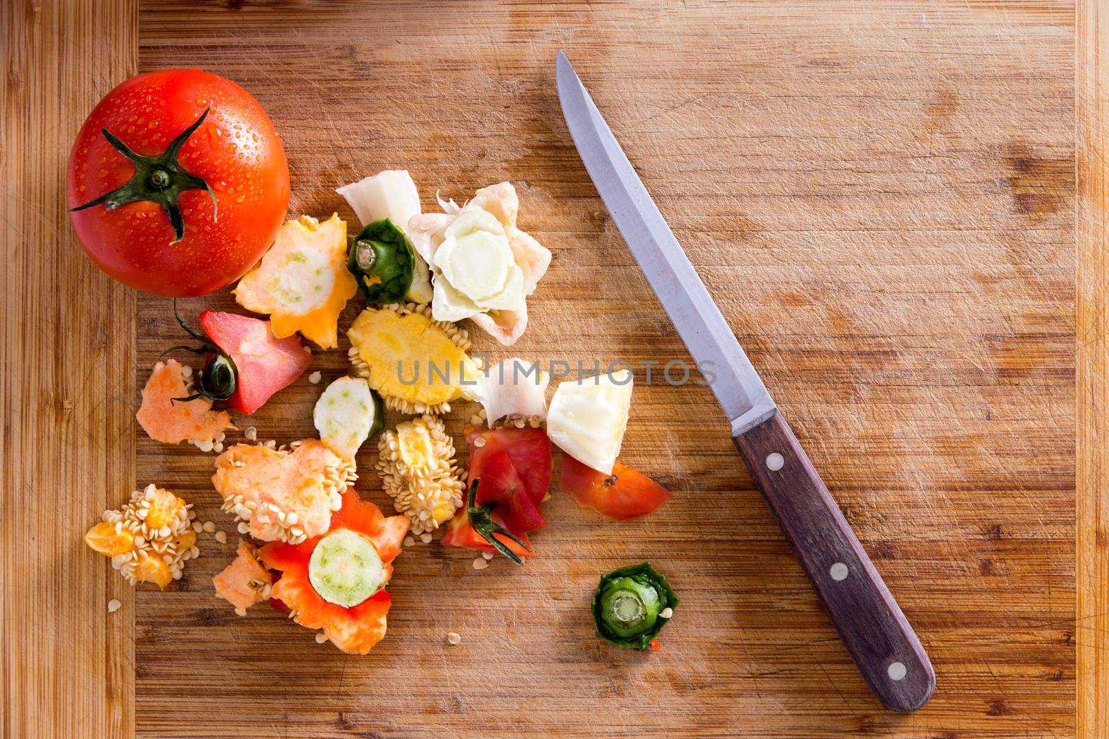 Organic Wastes from Veggies and Spices, Can be Used to Compost Garden Soil, on Top of Wooden Chopping Board with Kitchen Knife. Captured in High Angle View.
