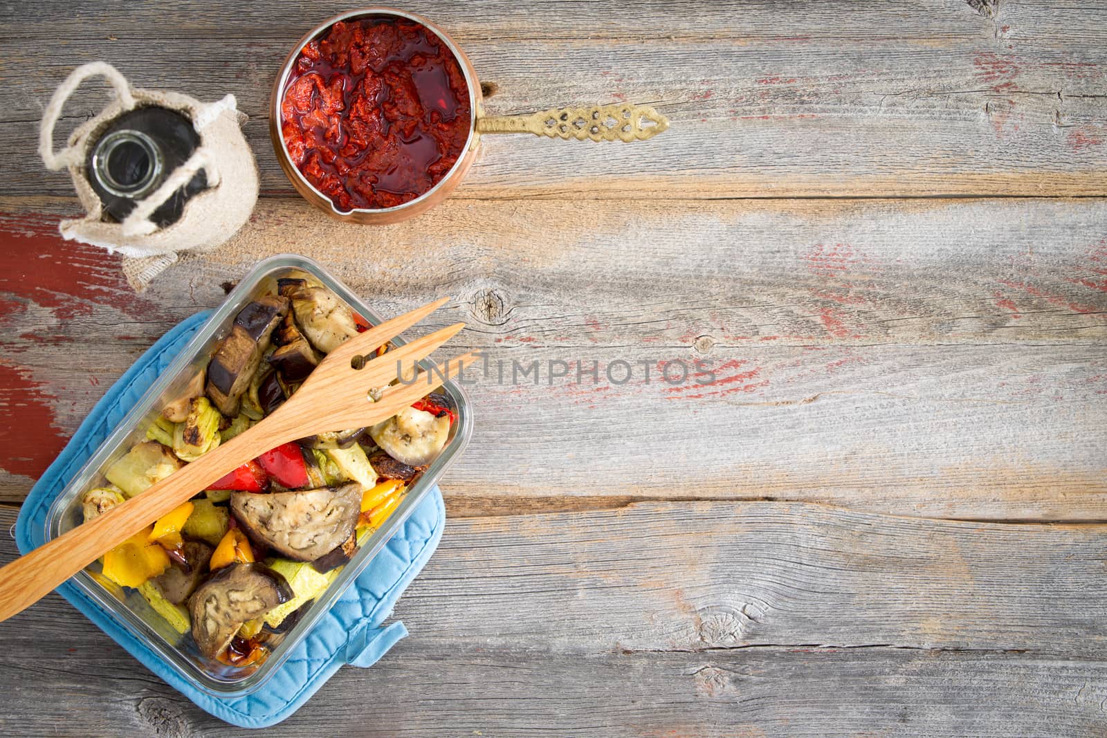 Healthy roast Turkish style vegetables served with a red hot pungent pepper paste and olive oil on a rustic wooden table with copyspace