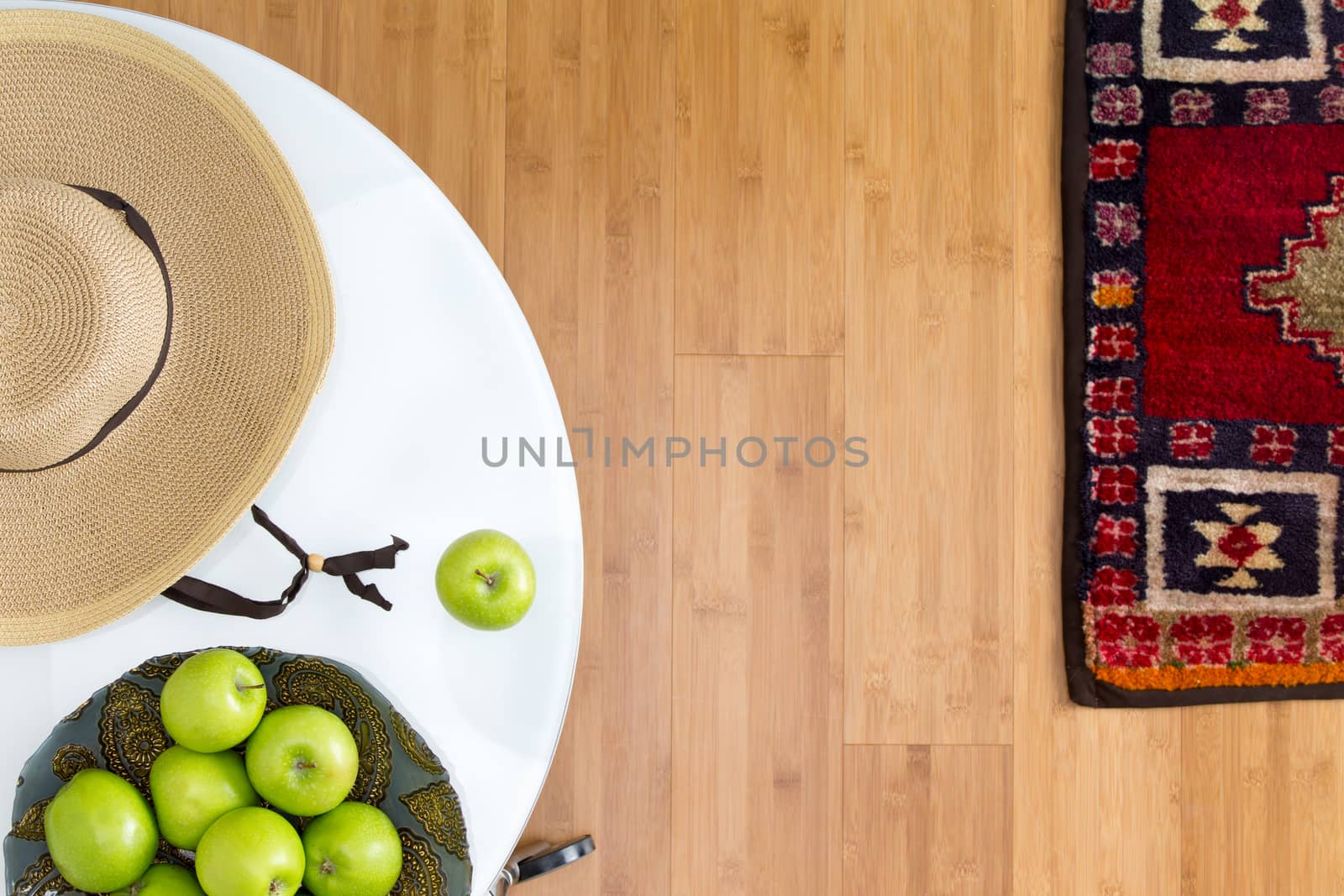 High Angle View of Healthy Fresh Green Apples and Brown Hat on Top of a White Table on the Wooden Floor with Carpet.