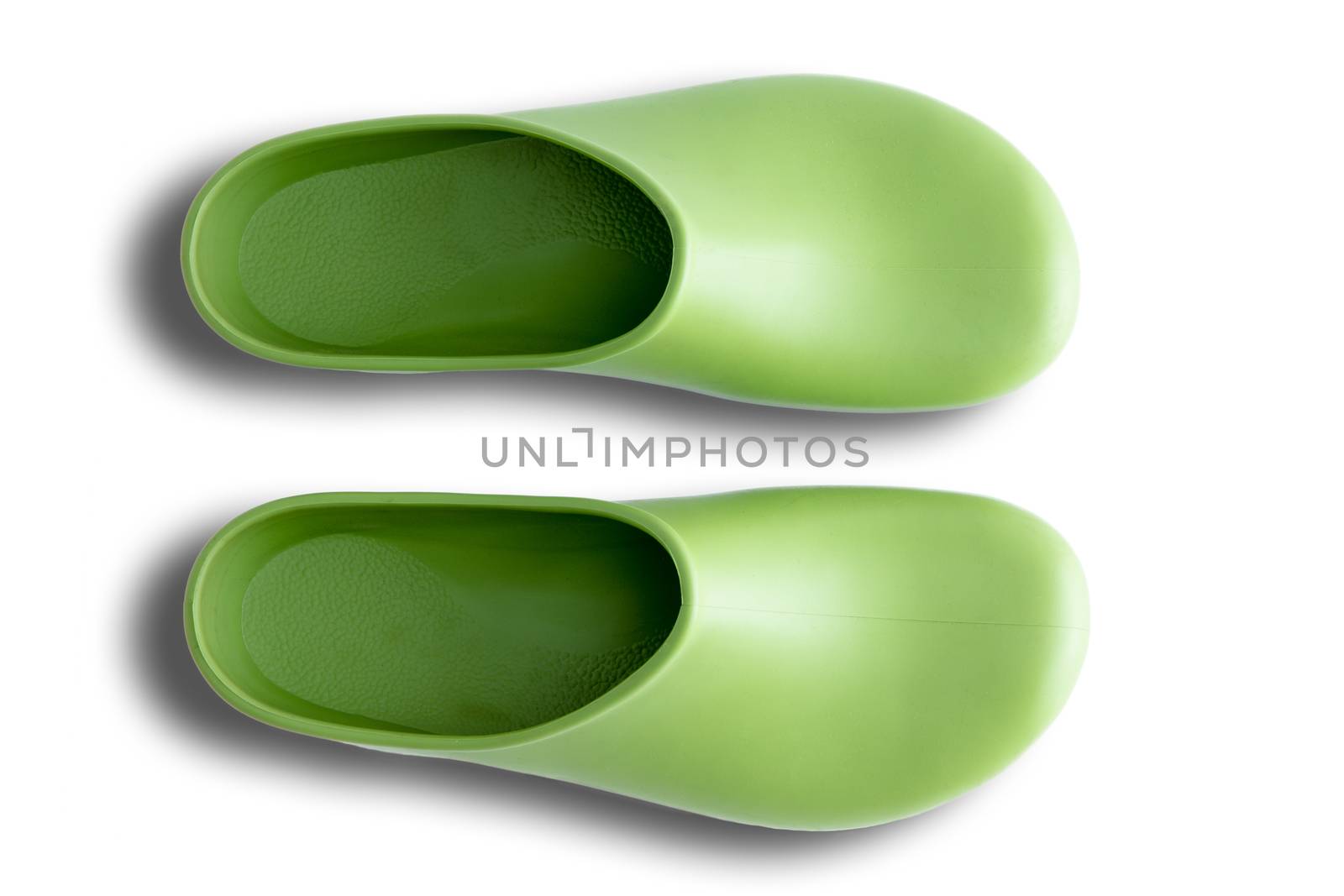 Pair of clean green simple clog form rubber gardening shoes neatly arranged side by side over a white background, overhead view