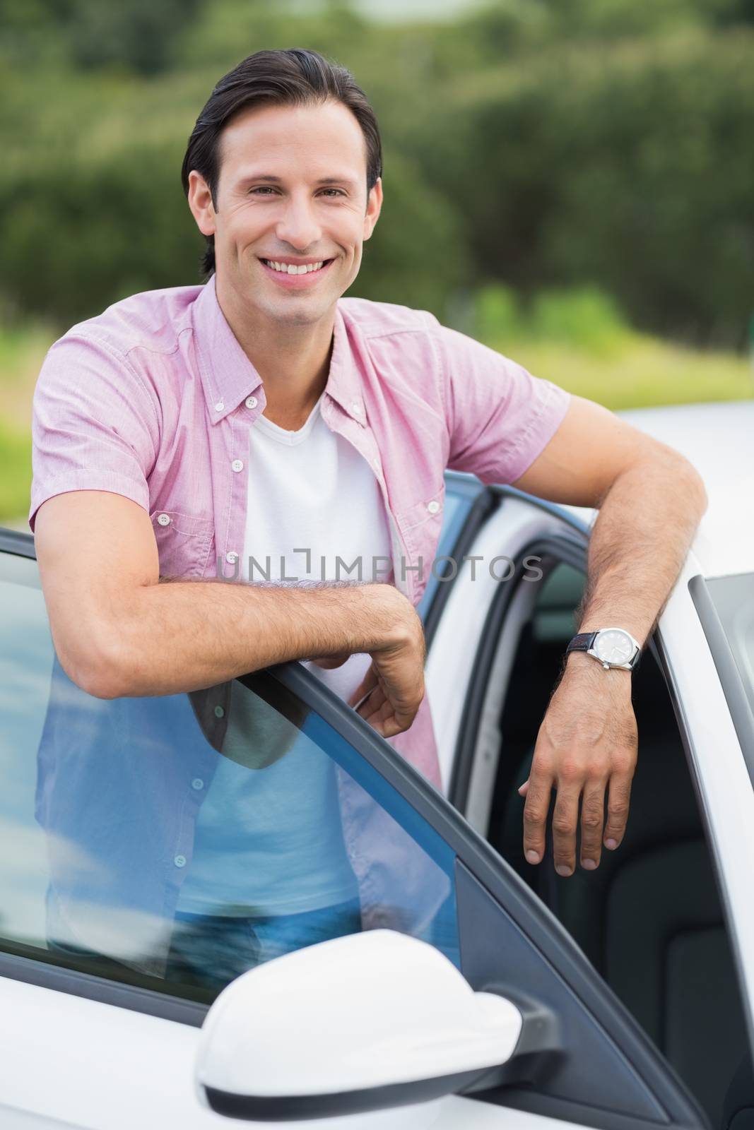 Man smiling at camera outside his car
