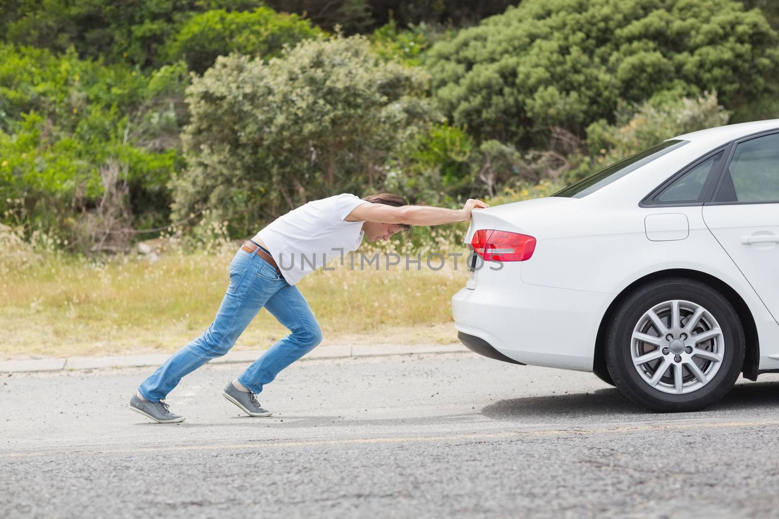 Man pushing his car at the side of the road