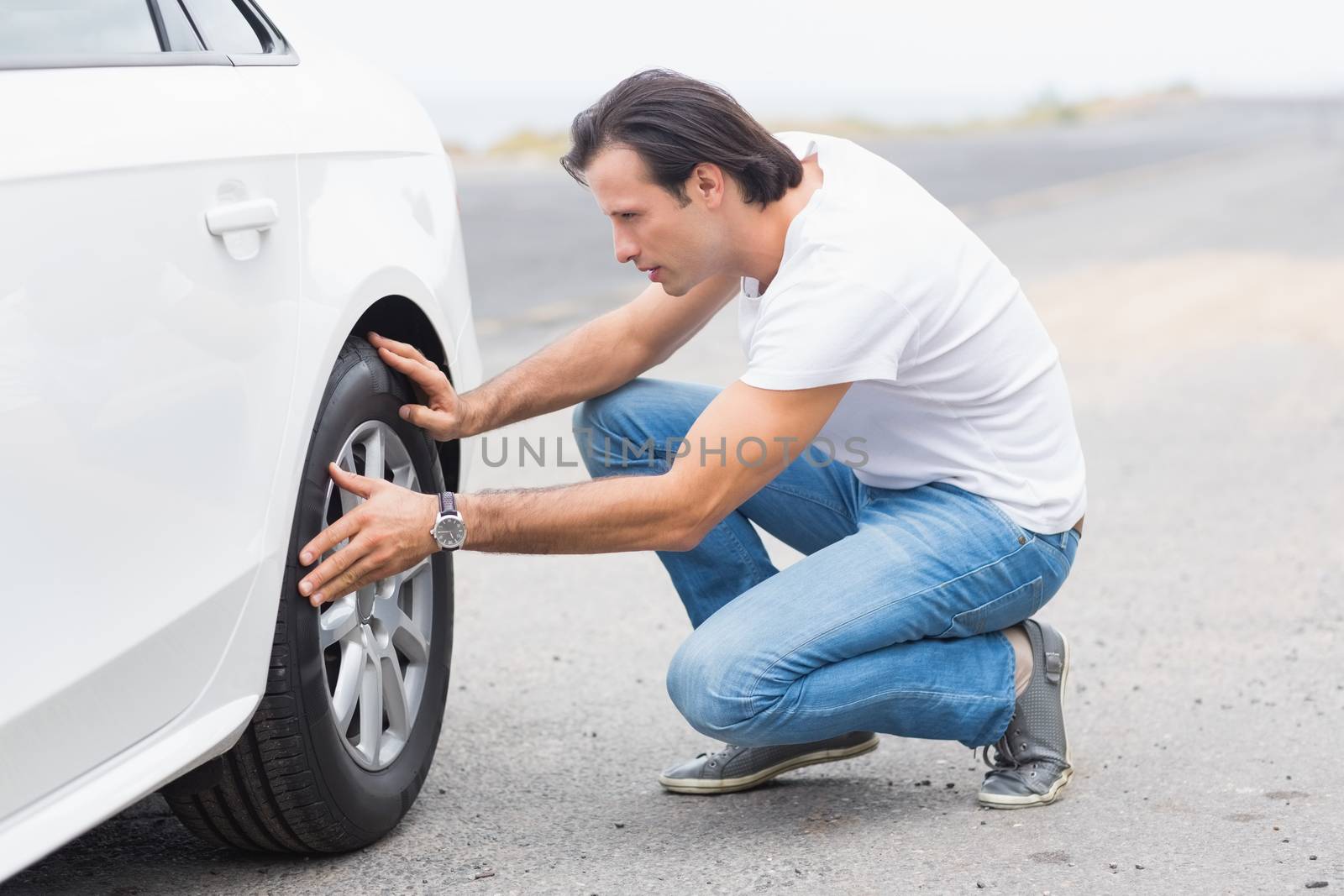 Man checking the wheels of his car 