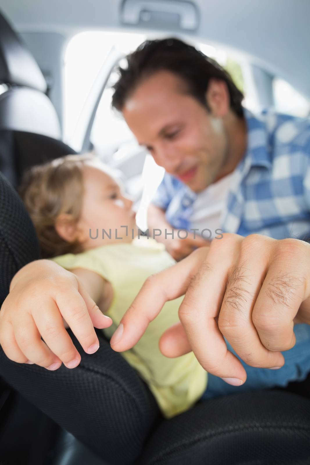 Father securing his baby in the car seat in his car