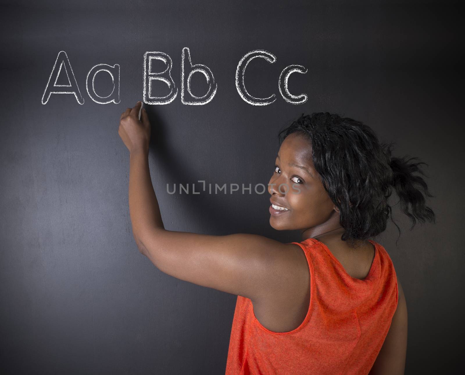 South African or African American woman teacher or student learn alphabet write writing on chalk blackboard background