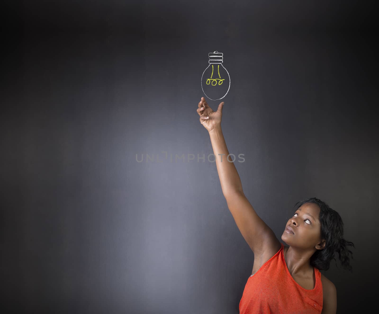 South African or African American woman teacher or student bright idea chalk lightbulb thinking blackboard background by alistaircotton