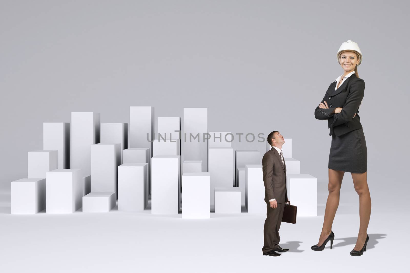 Small businessman in suit with briefcase looking at large businesswoman in suit and helmet. Many white cubes as backdrop