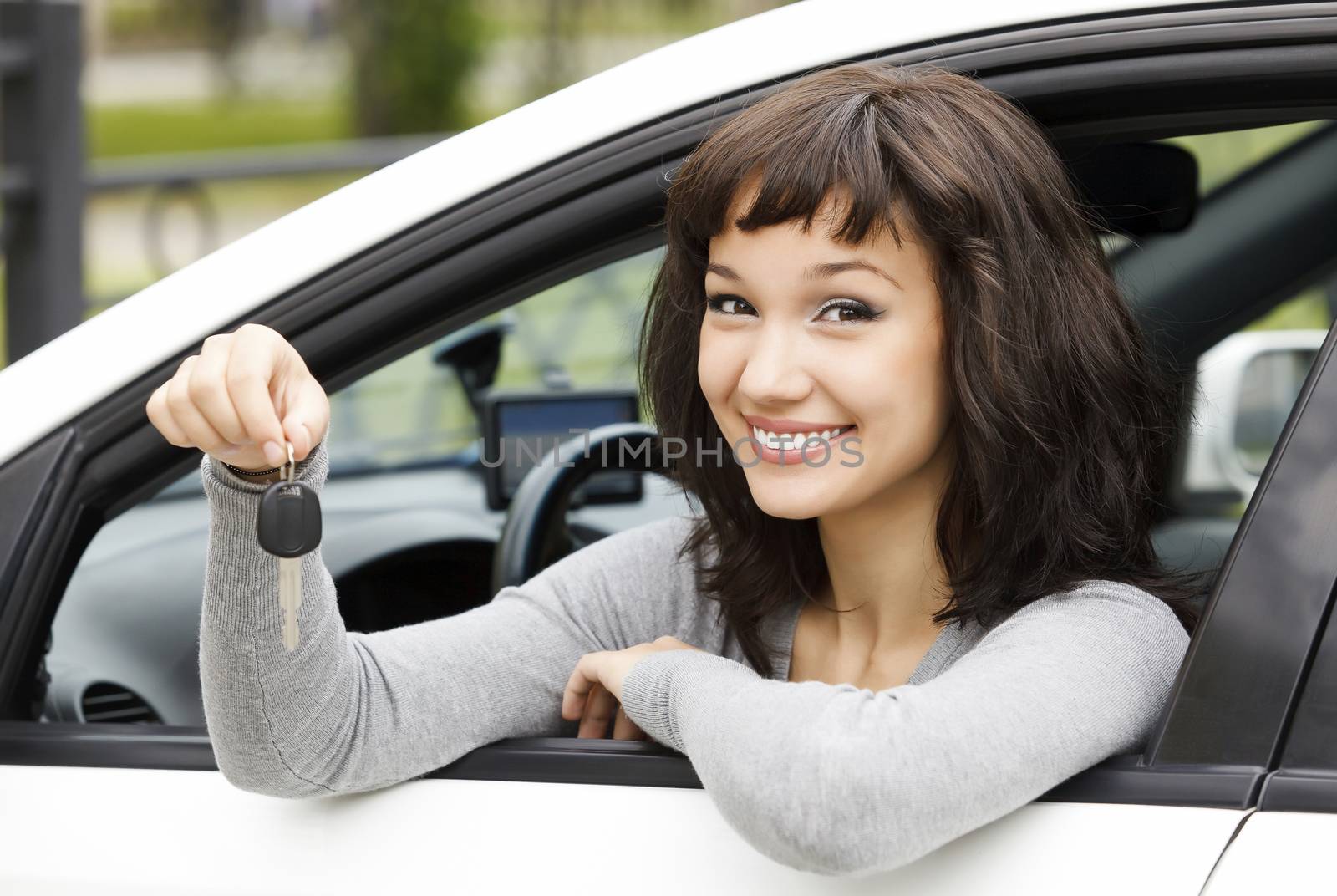 Pretty female driver in a white car showing the car key