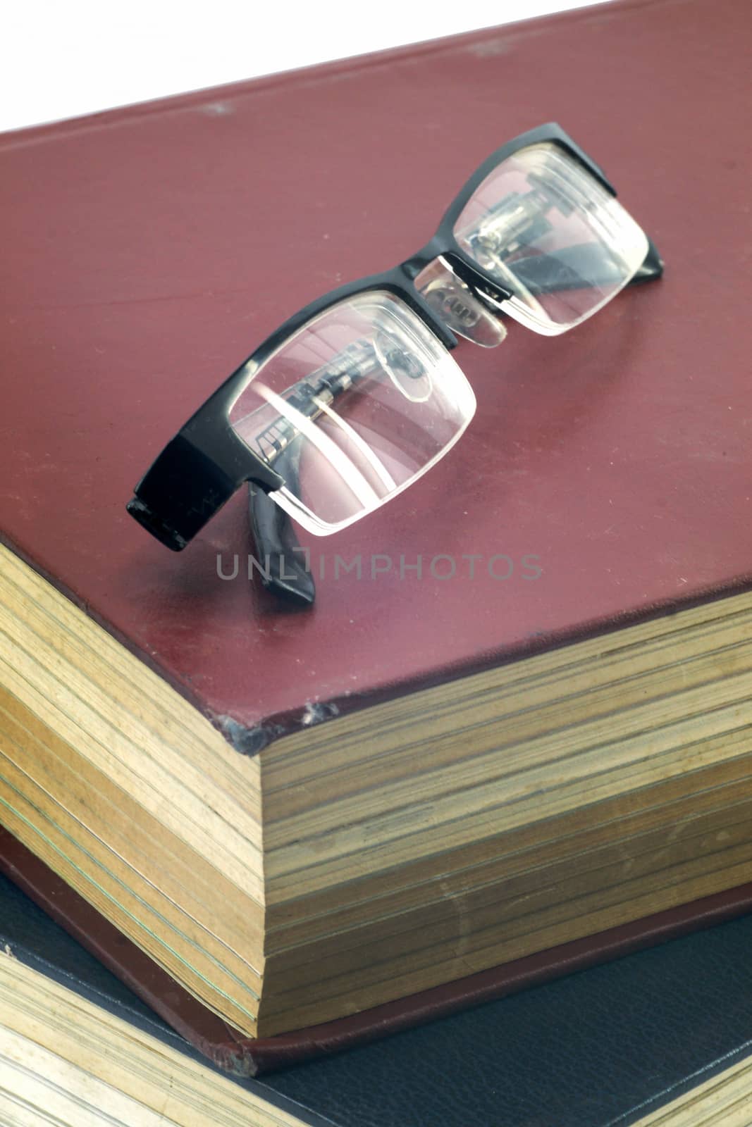 Old text books or bible with eyeglasses on them by mranucha