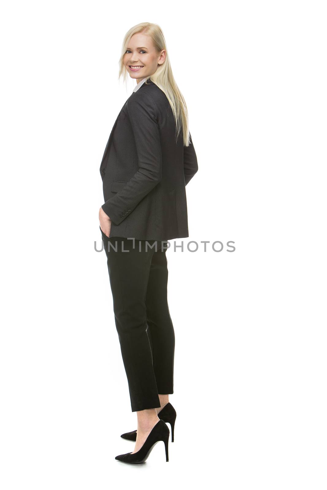 blonde businesswoman turning towards camera, hands in pockets