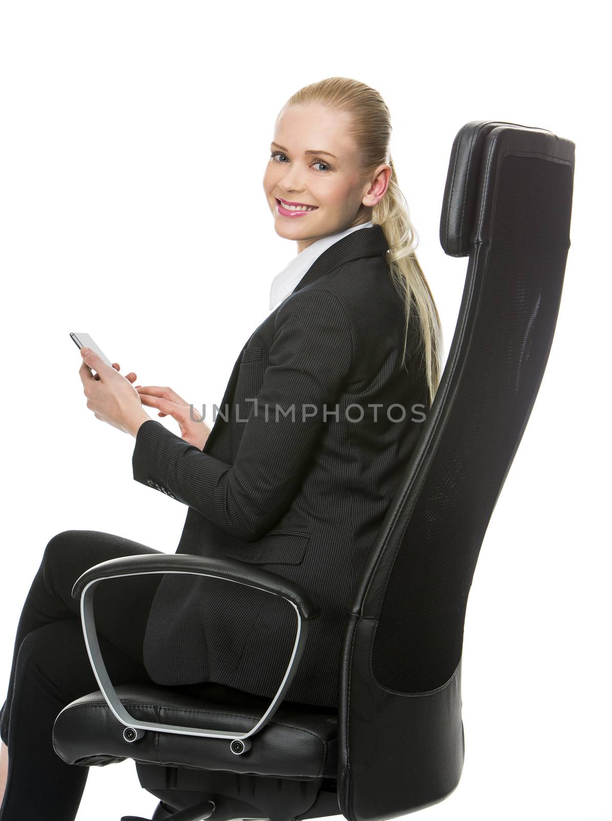 blonde smiling businesswoman seated on a chair working with tablet