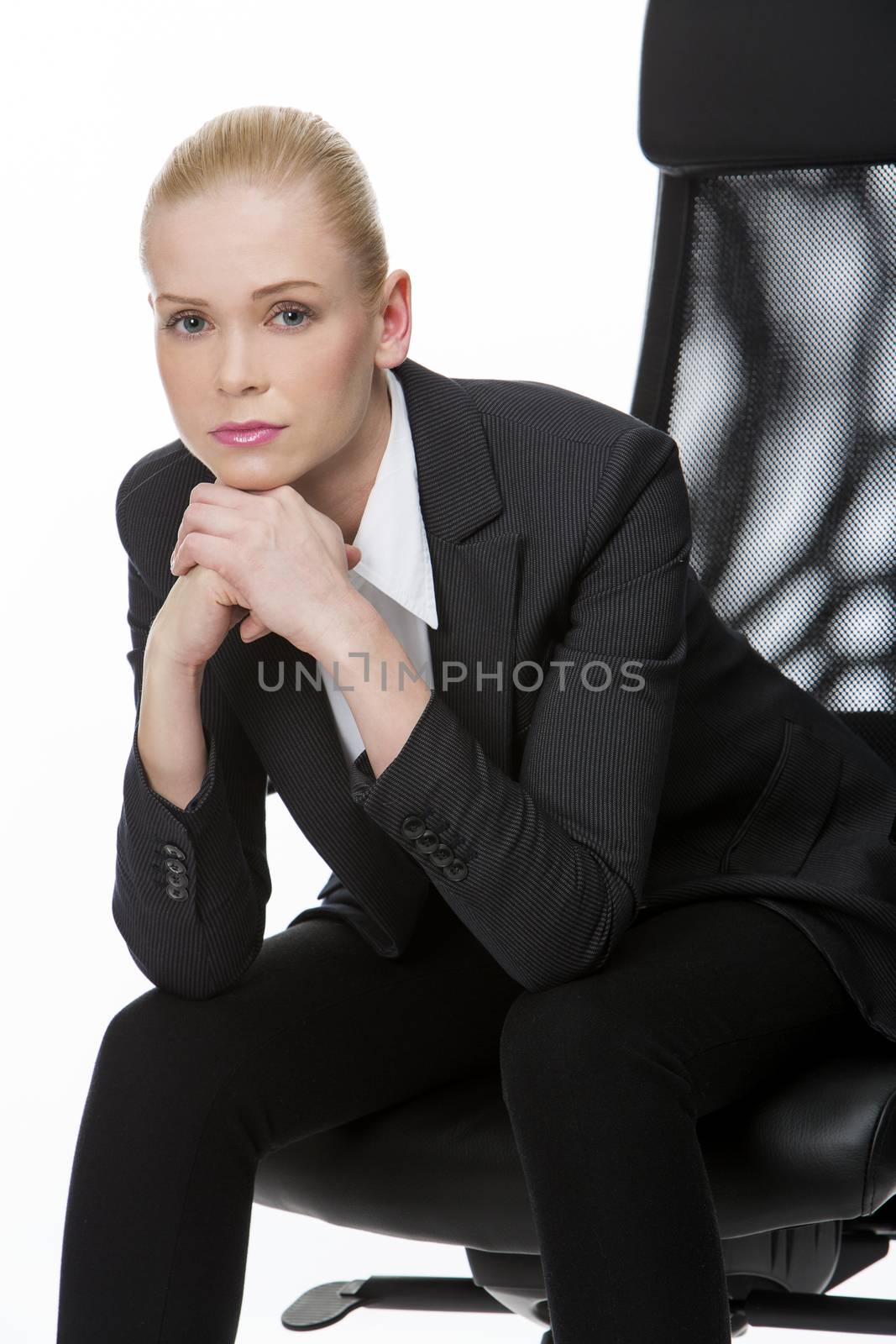 blonde serious businesswoman seated on a chair with hands below chin