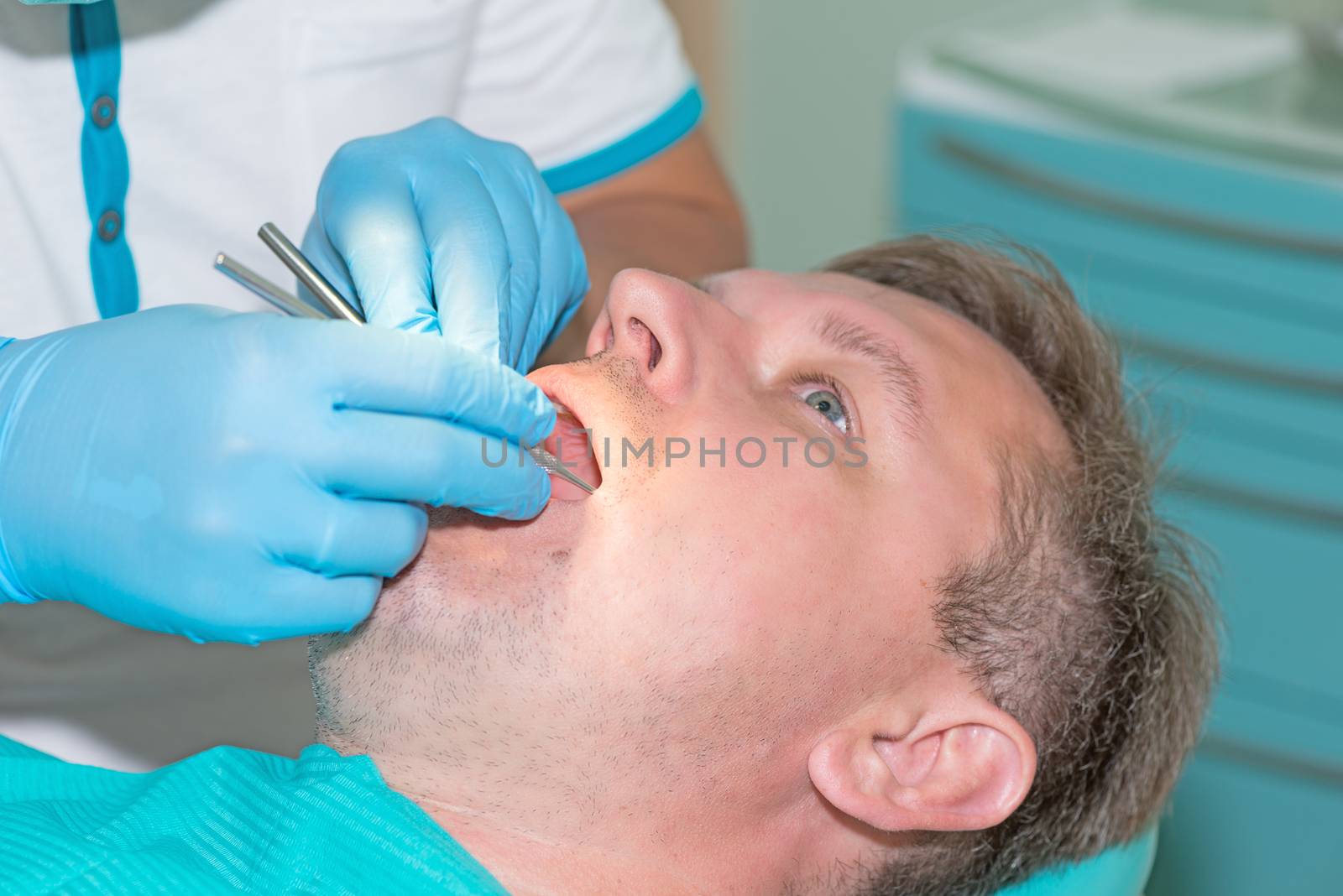 man in dentist office doing annual check up by Nanisimova