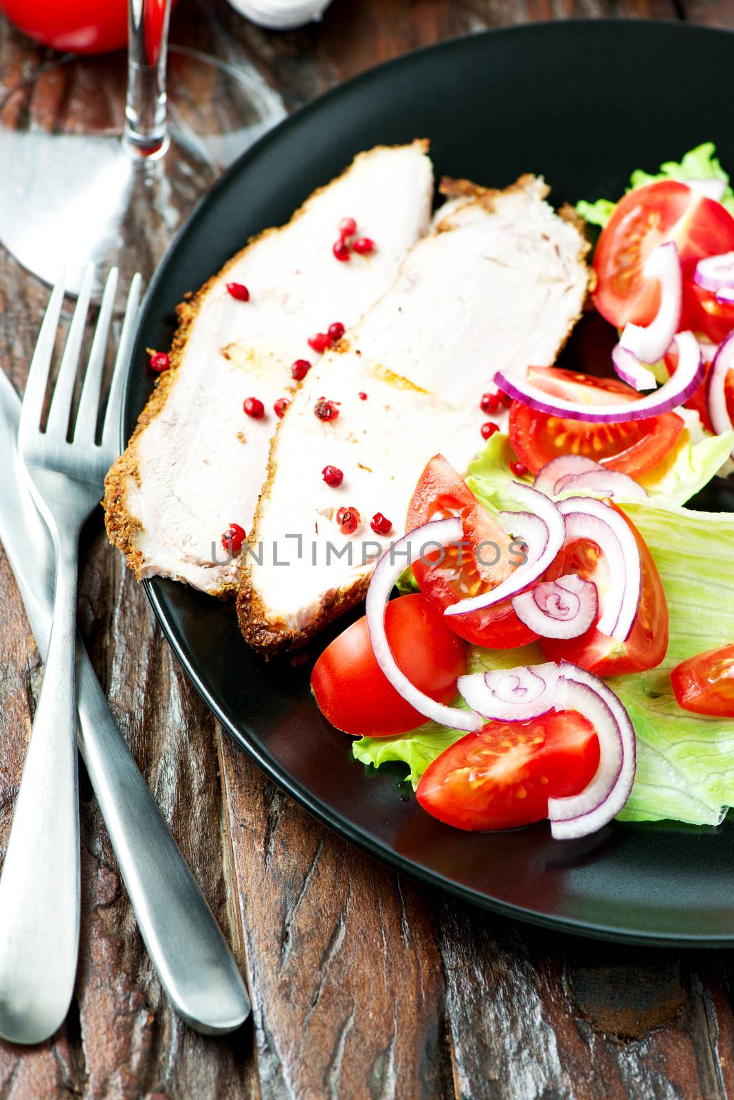 Set of oven baked pork in plate with vegetable salad on old wooden table