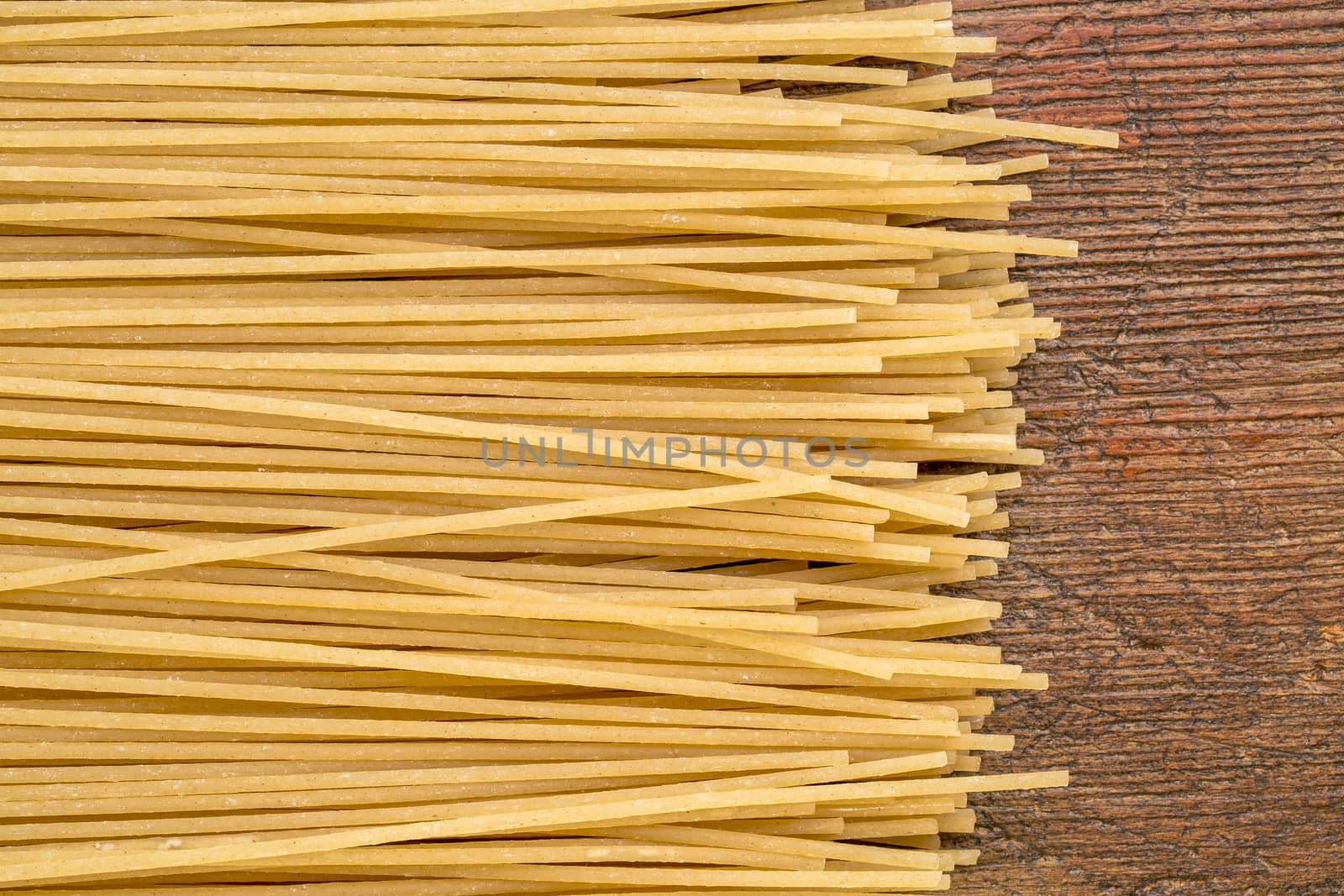 uncooked gluten free, brown rice pasta, spaghetti style on a rustic wood table