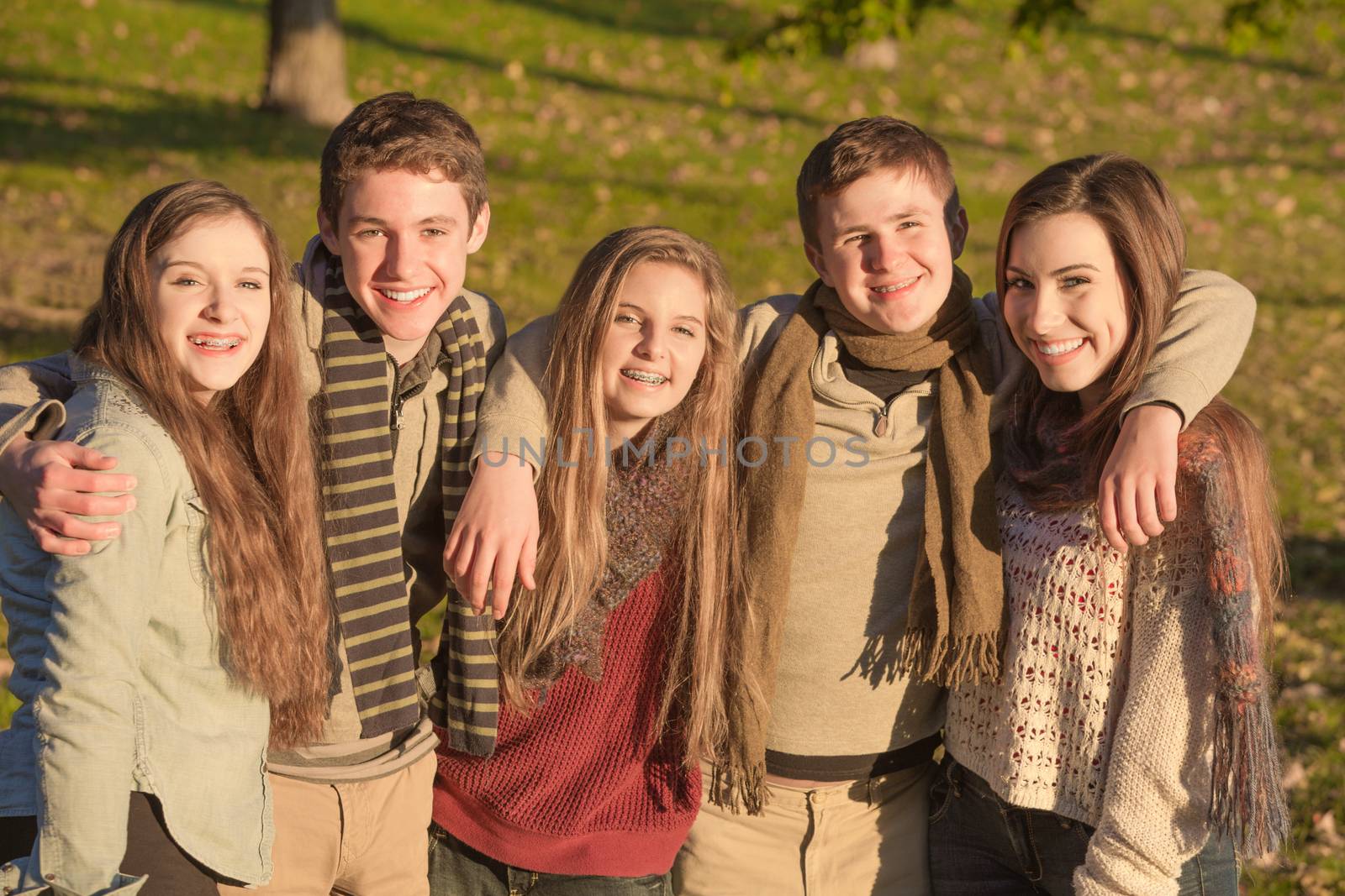 Cute group of European teenagers embracing each other