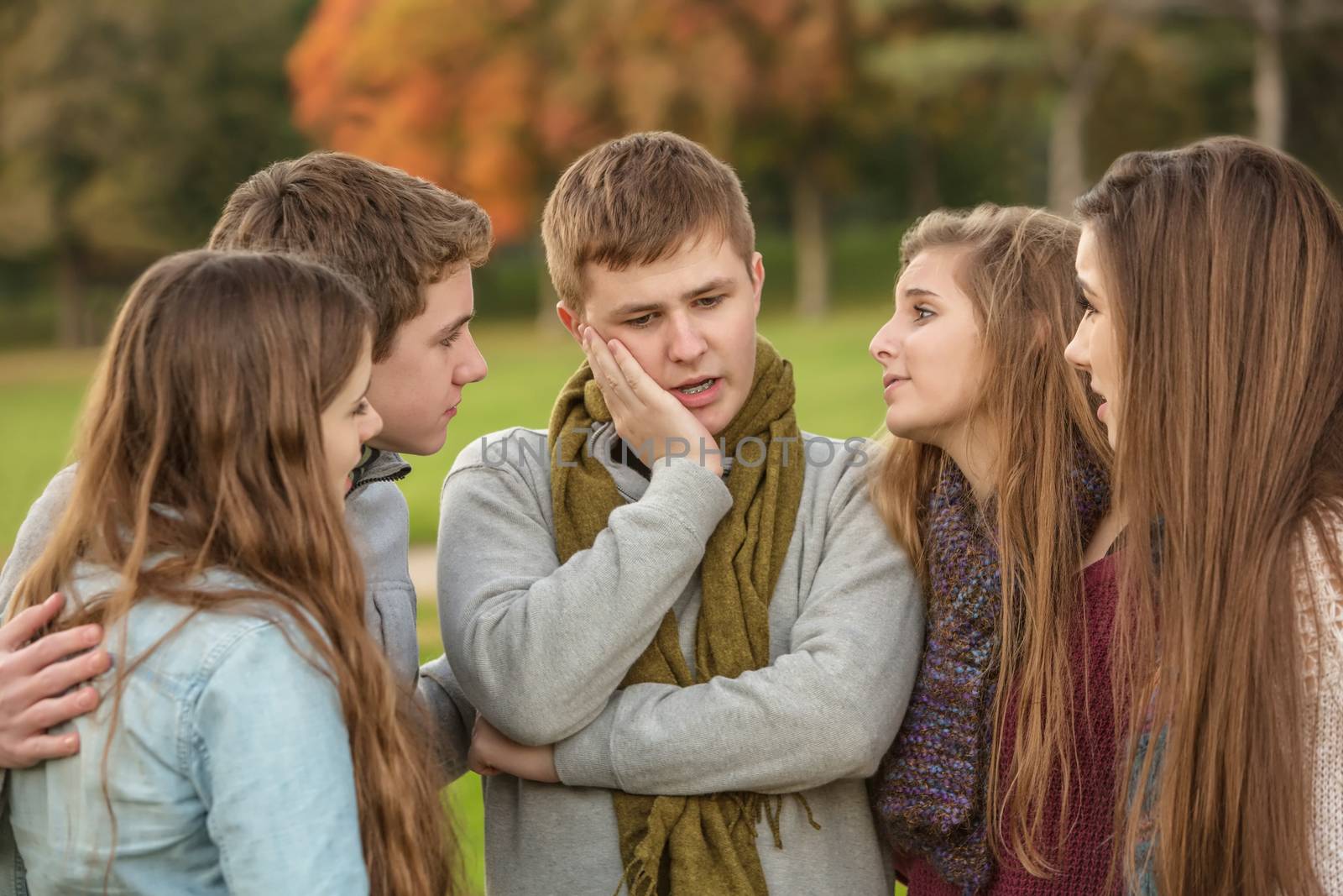 Young male teen with confused expression and friends