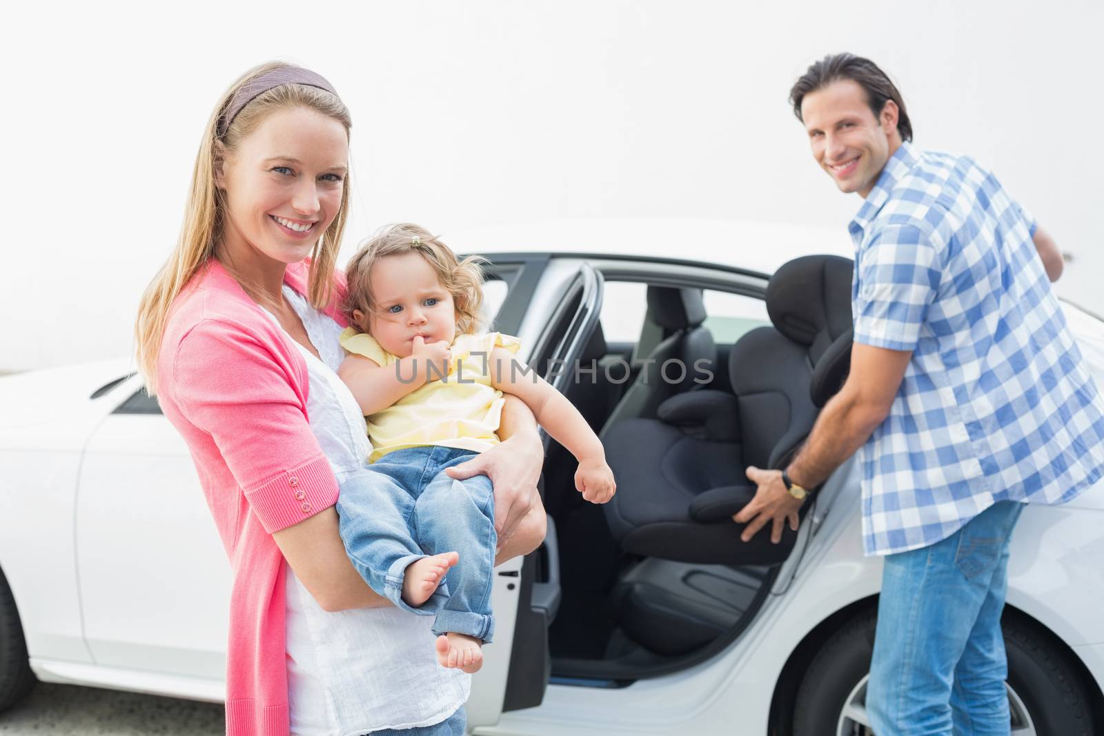 Parents carrying baby and her car seat out of the car