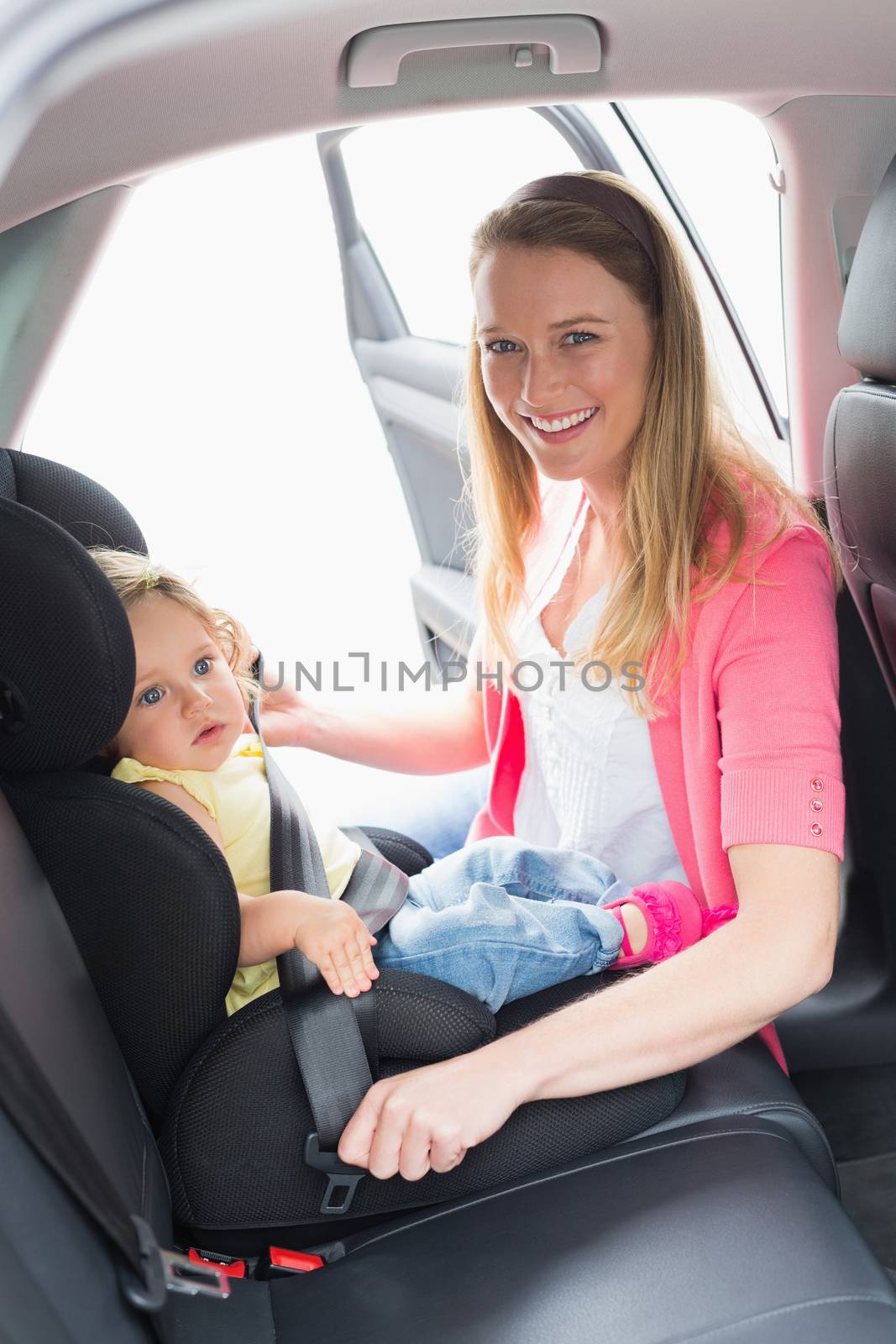 Mother securing her baby in the car seat in her car