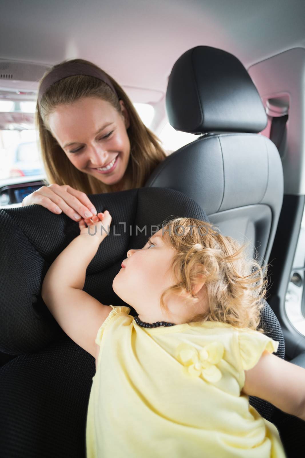 Mother checking her baby in the car seat in her car