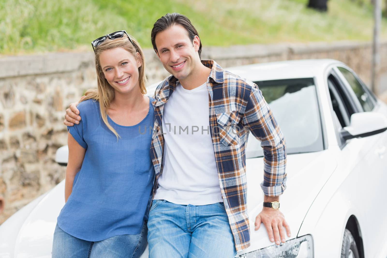 Couple leaning on the bonnet of their car 