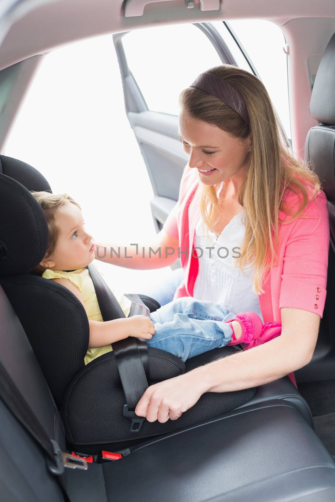 Mother securing her baby in the car seat by Wavebreakmedia