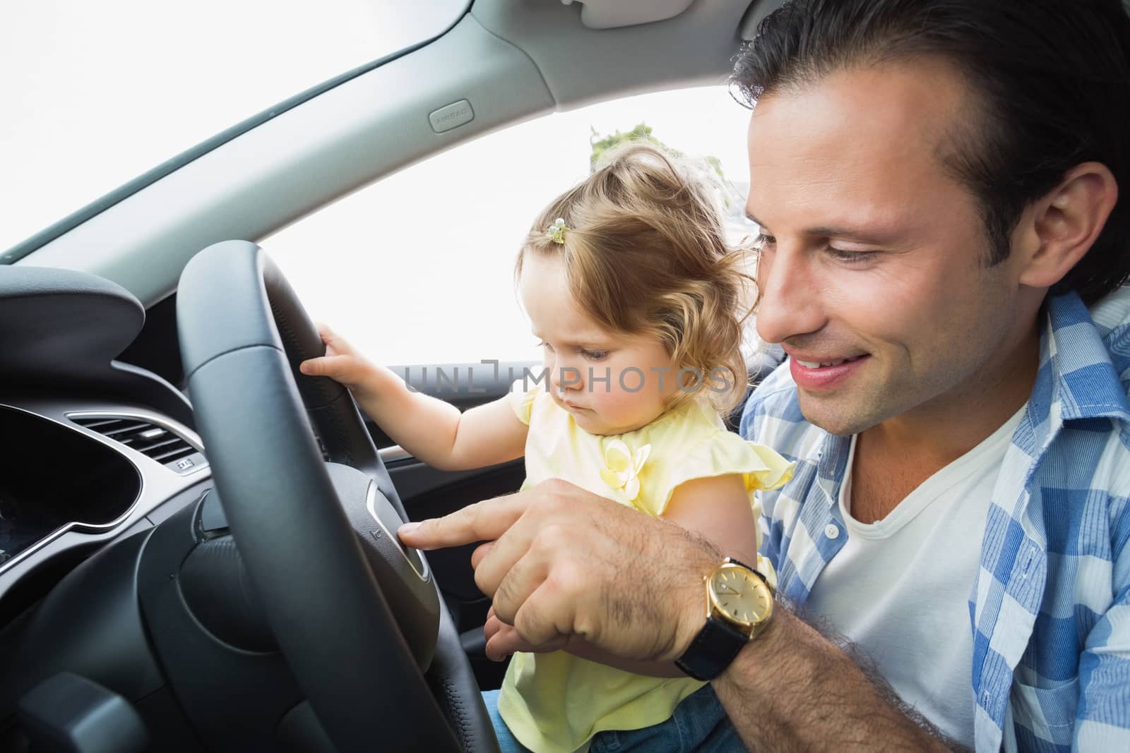 Father playing with baby in drivers seat in his car