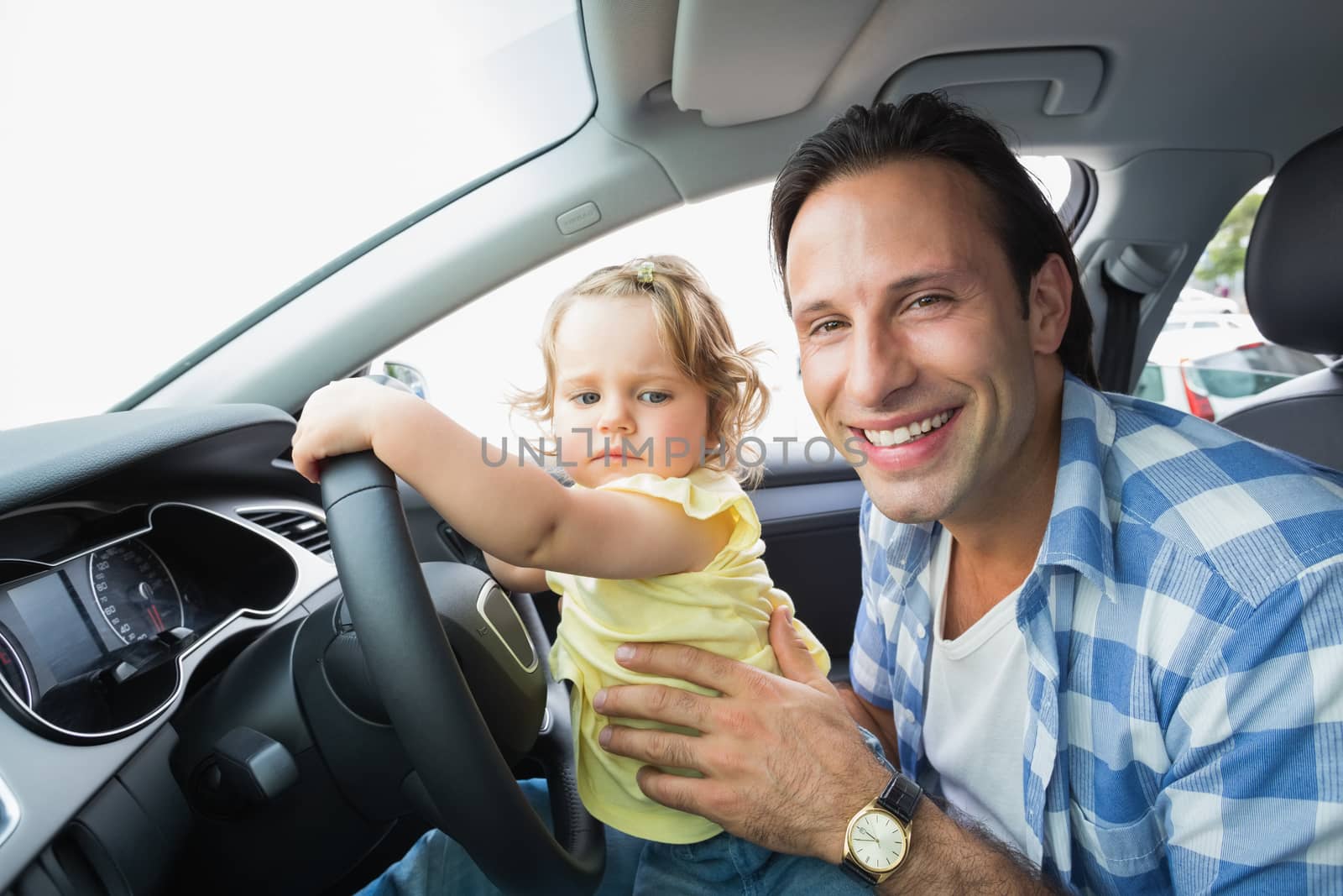 Father playing with baby in drivers seat in his car