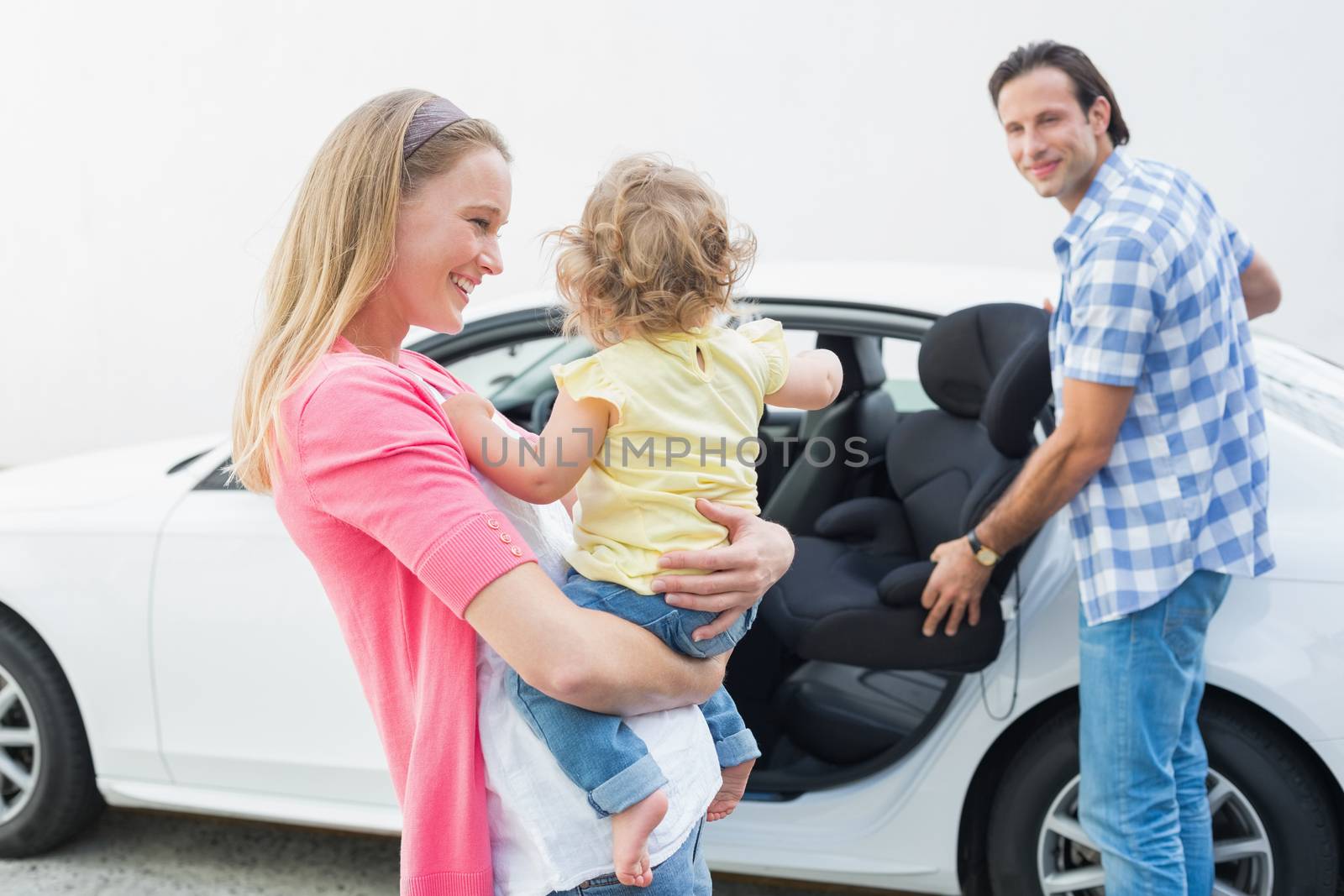 Parents carrying baby and her car seat by Wavebreakmedia