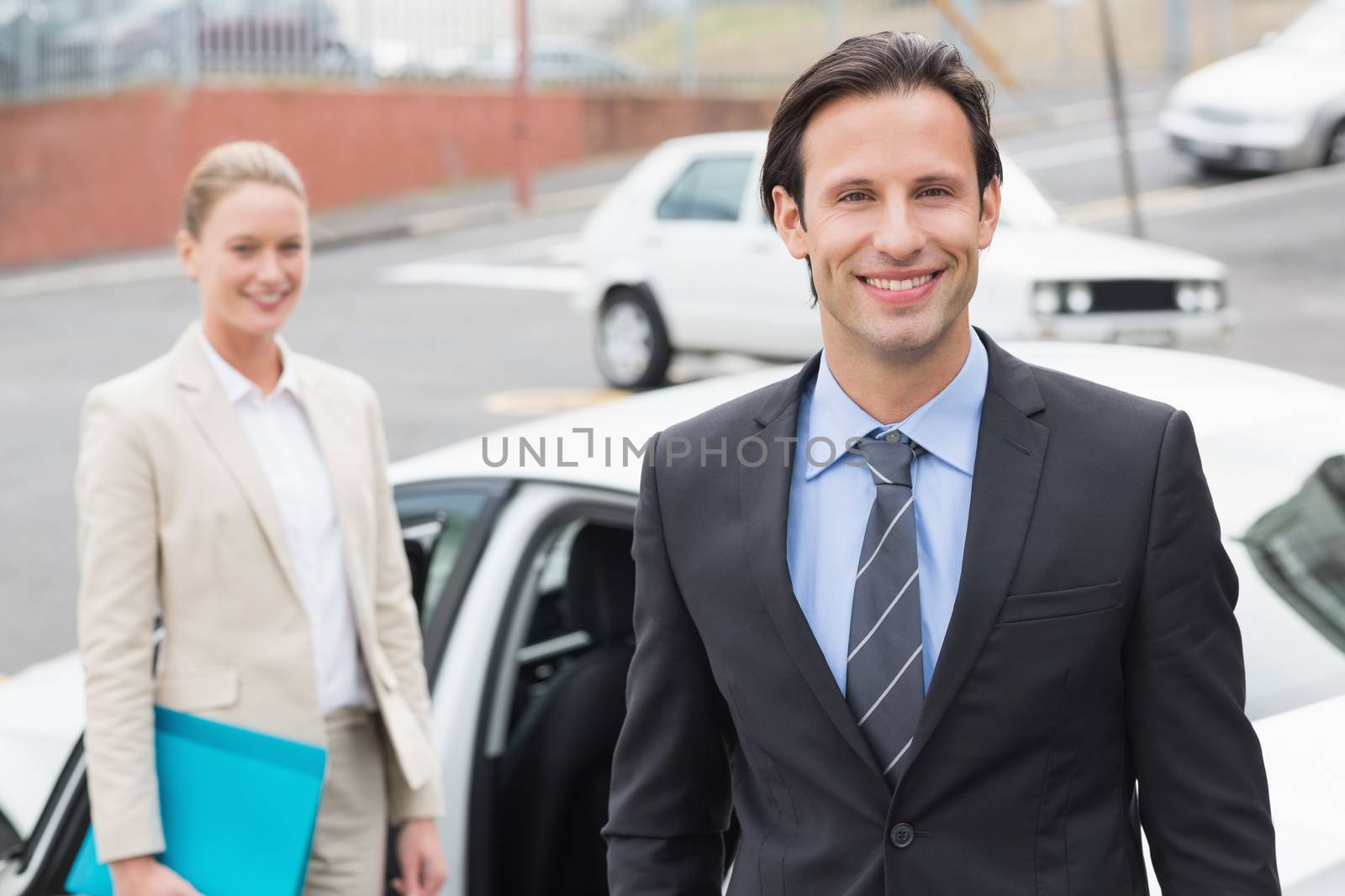 Team of businessman smiling at camera outside the car 