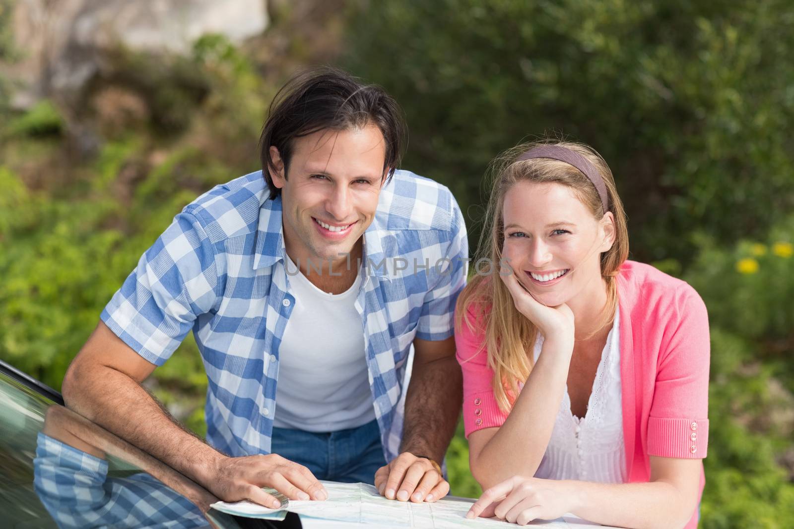 Smiling couple looking at a map outside their car 