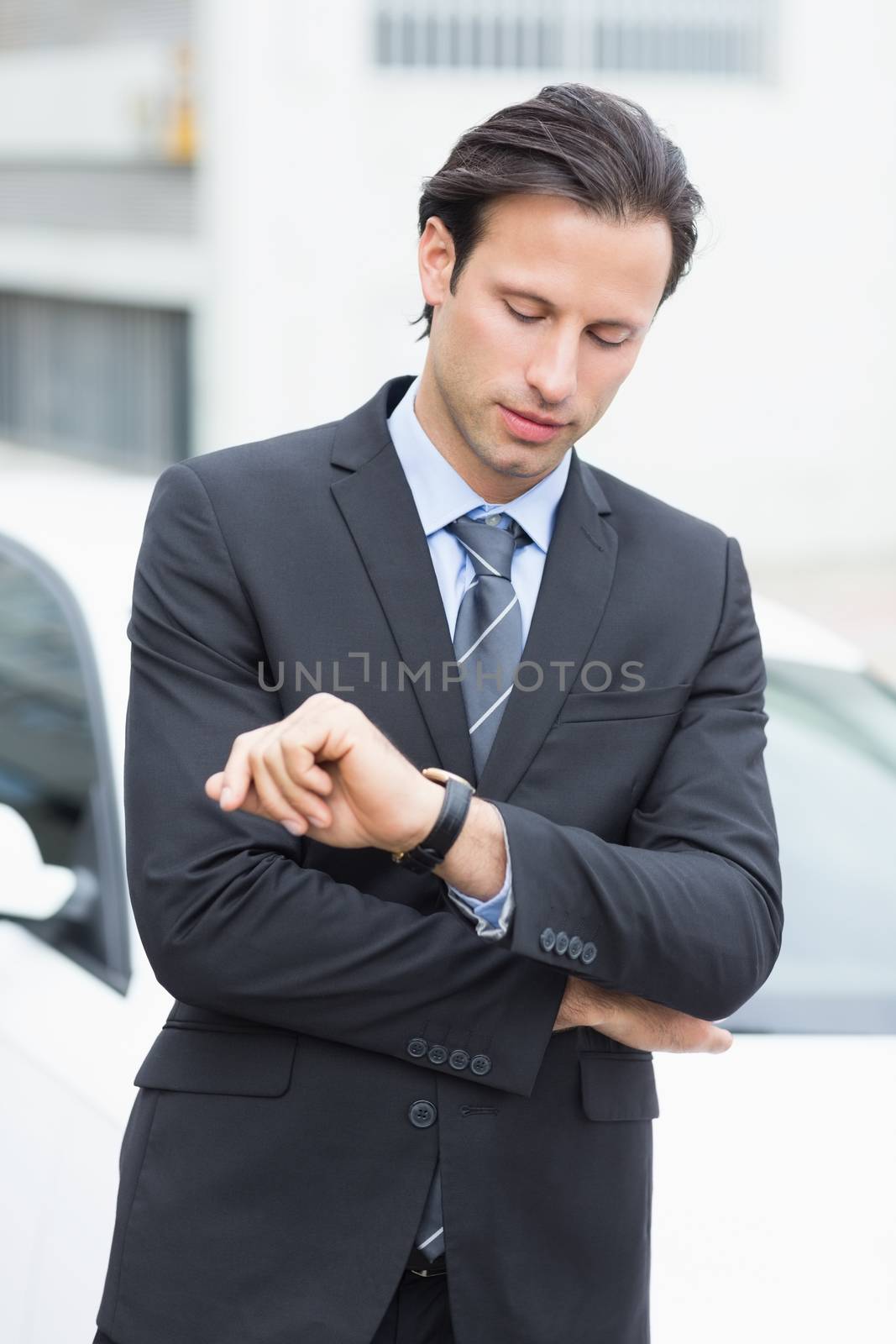 Businessman checking time outside his car 