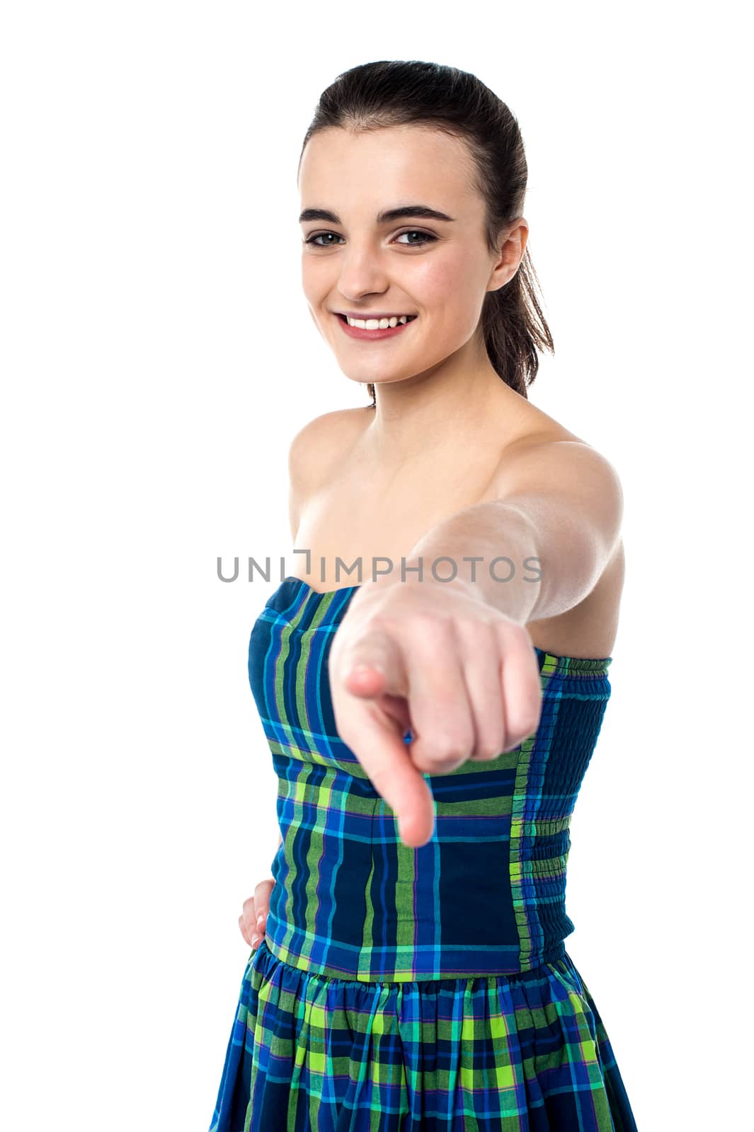 Pretty young smiling teenager pointing towards you.