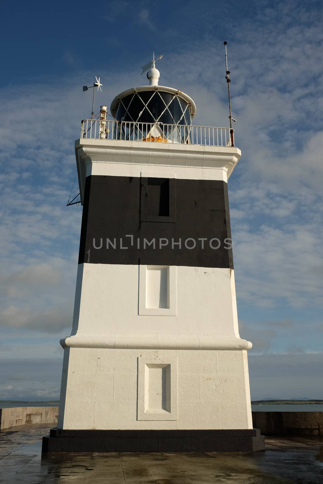 The lighthouse at the Holyhead breakwater, Anglesey, Wales, UK. Set against a blue sky with light cloud.