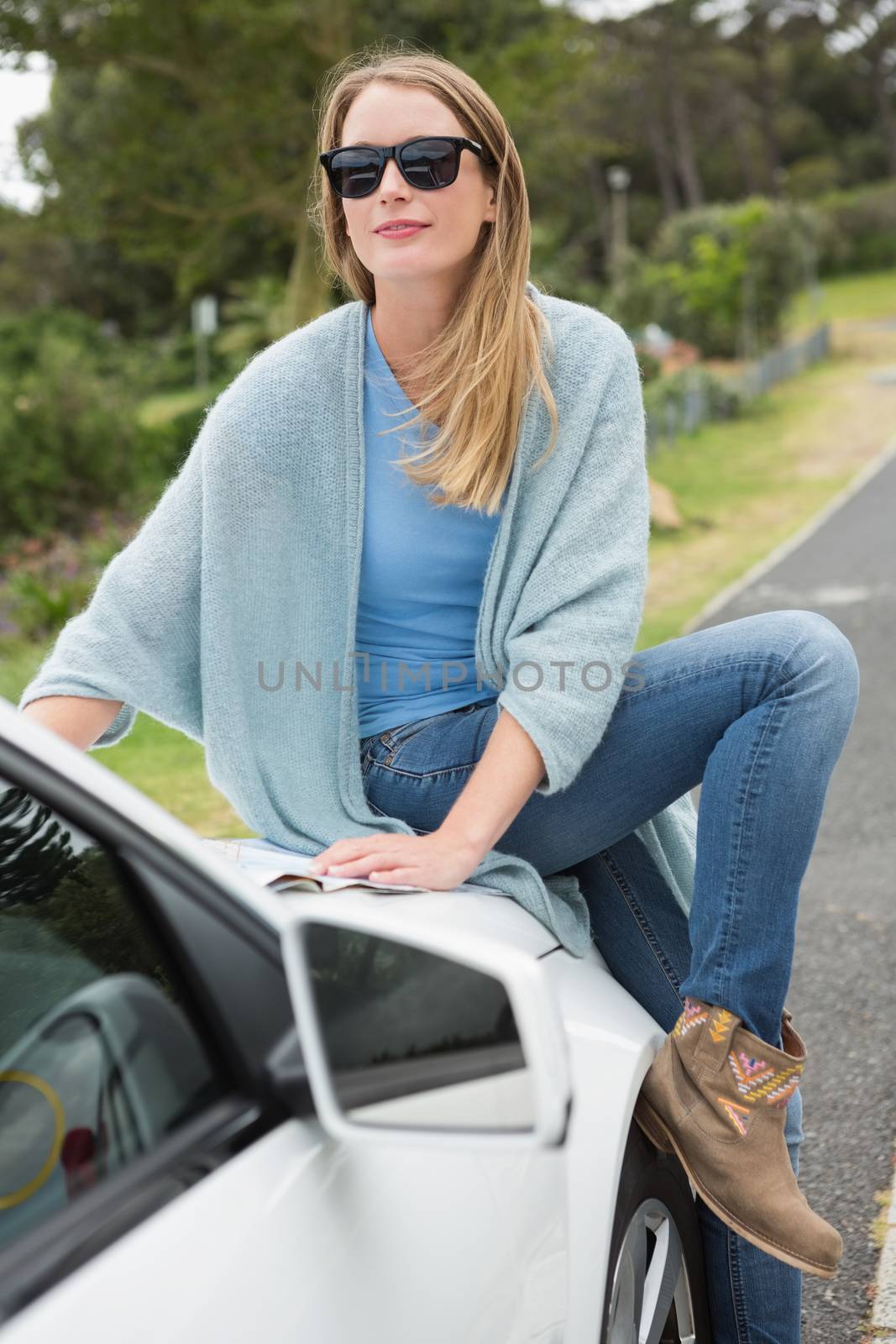 Young woman reading a map beside her car